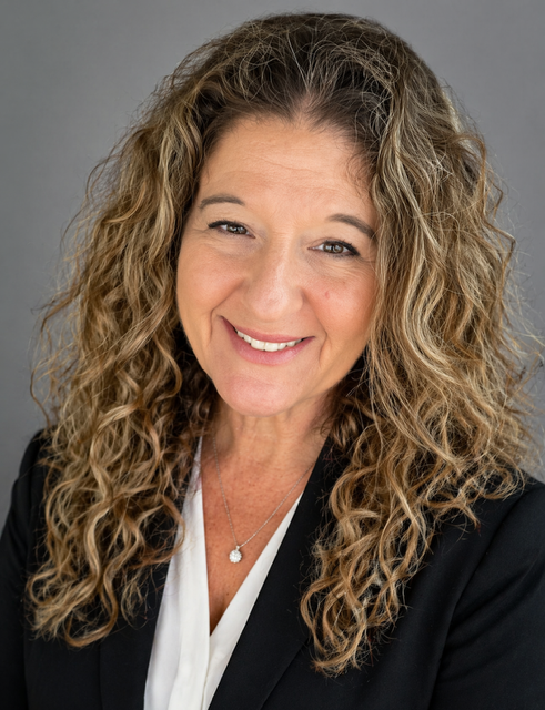 Close-up of a woman with curly hair smiling.