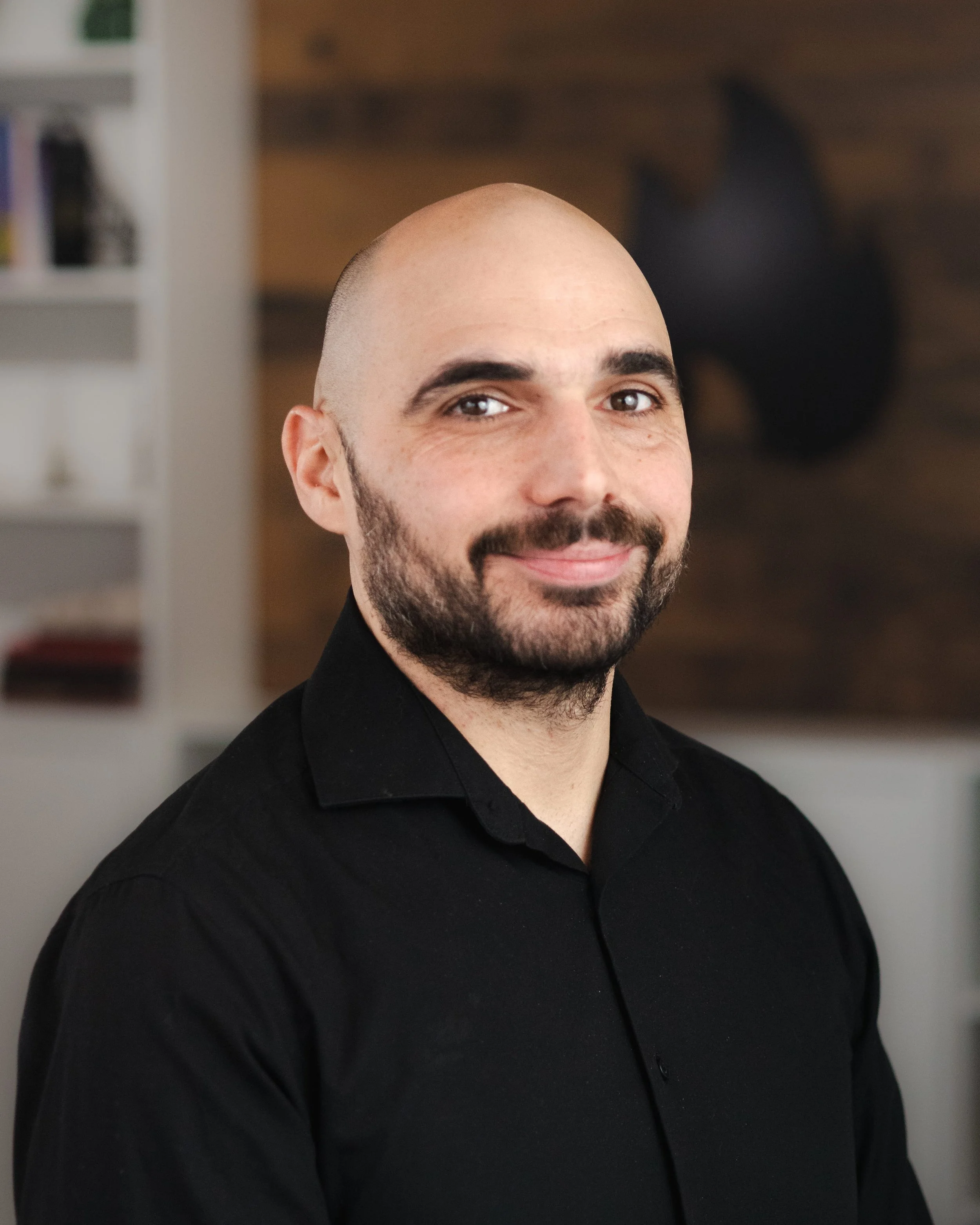 Portrait d'un homme souriant, chauve, portant un t-shirt noir.