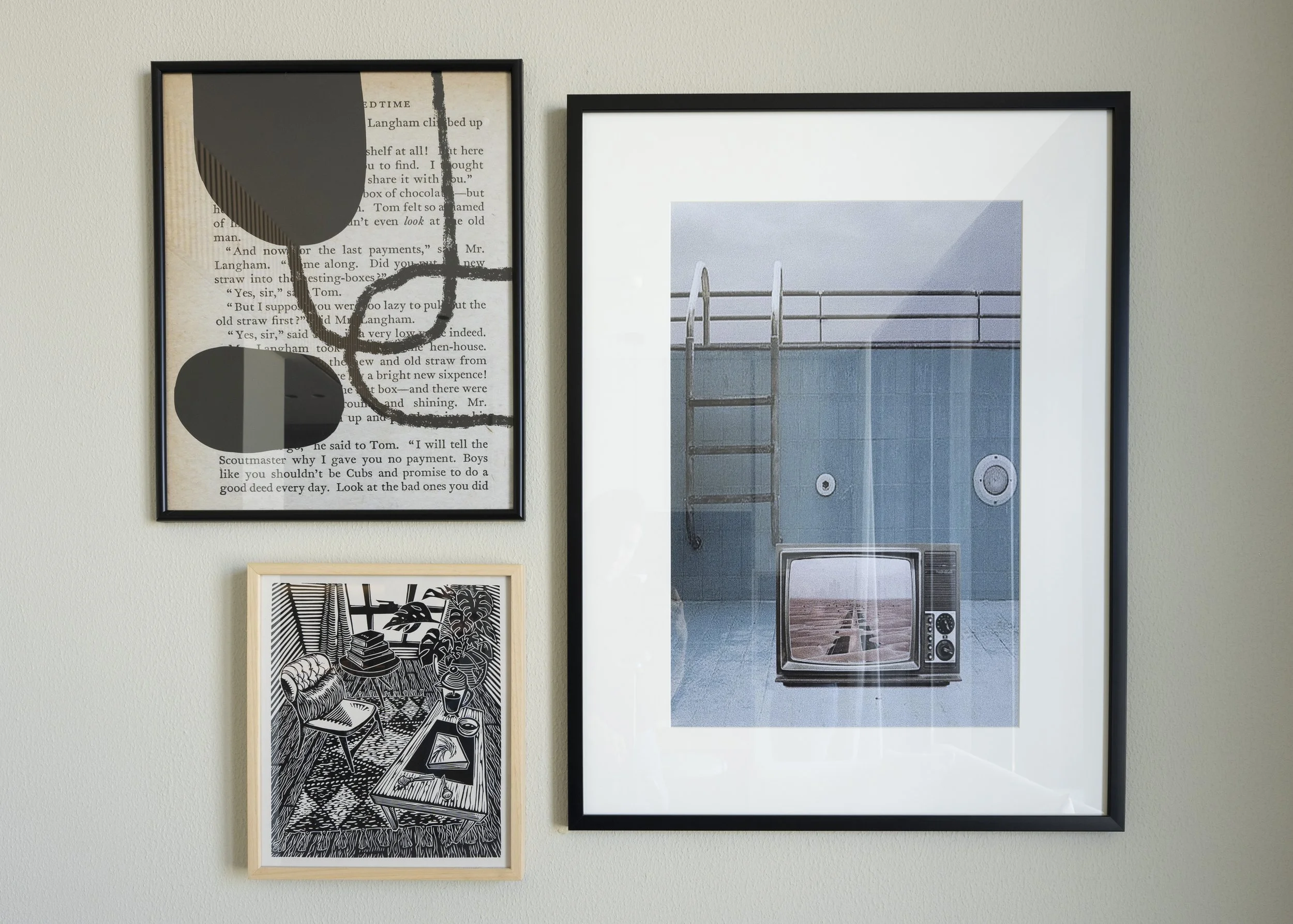 Several framed artworks including black geometric shapes atop the page of a book, a television inside an empty pool displaying a desert road, and a furniture filled room drawn in black and white.