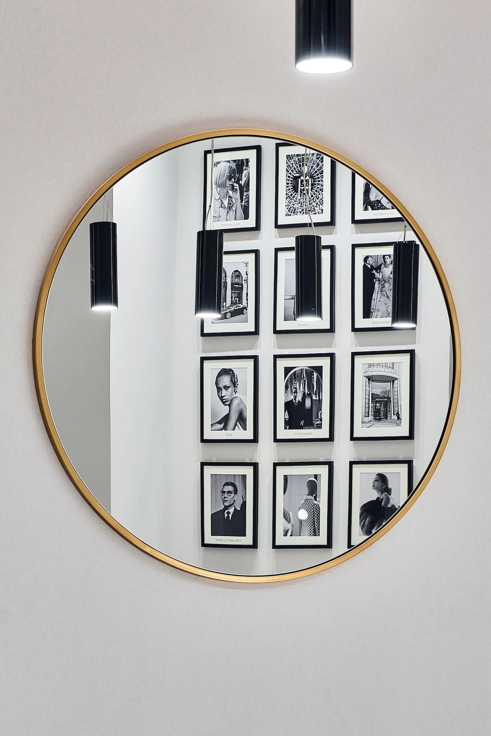 A large round mirror reflecting framed photographs on the opposite wall.