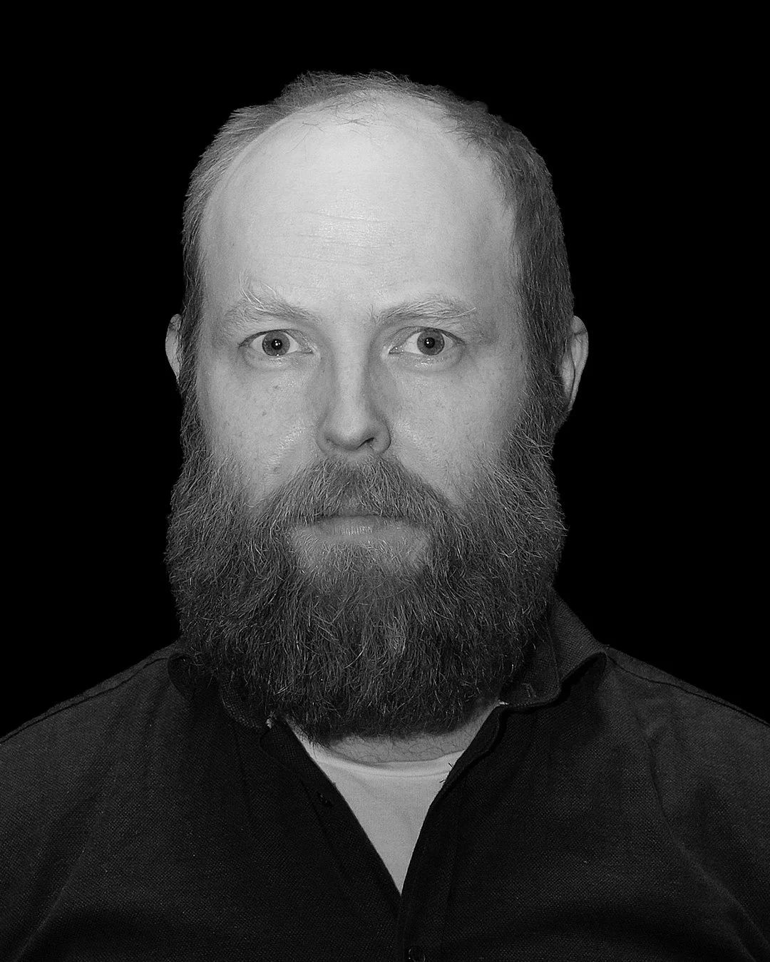 IMPROV COMEDY GBG Göteborg impro Man står med mikrofonstr utan att tala, belysning riktad mot ansiktet, mörk bakgrund.