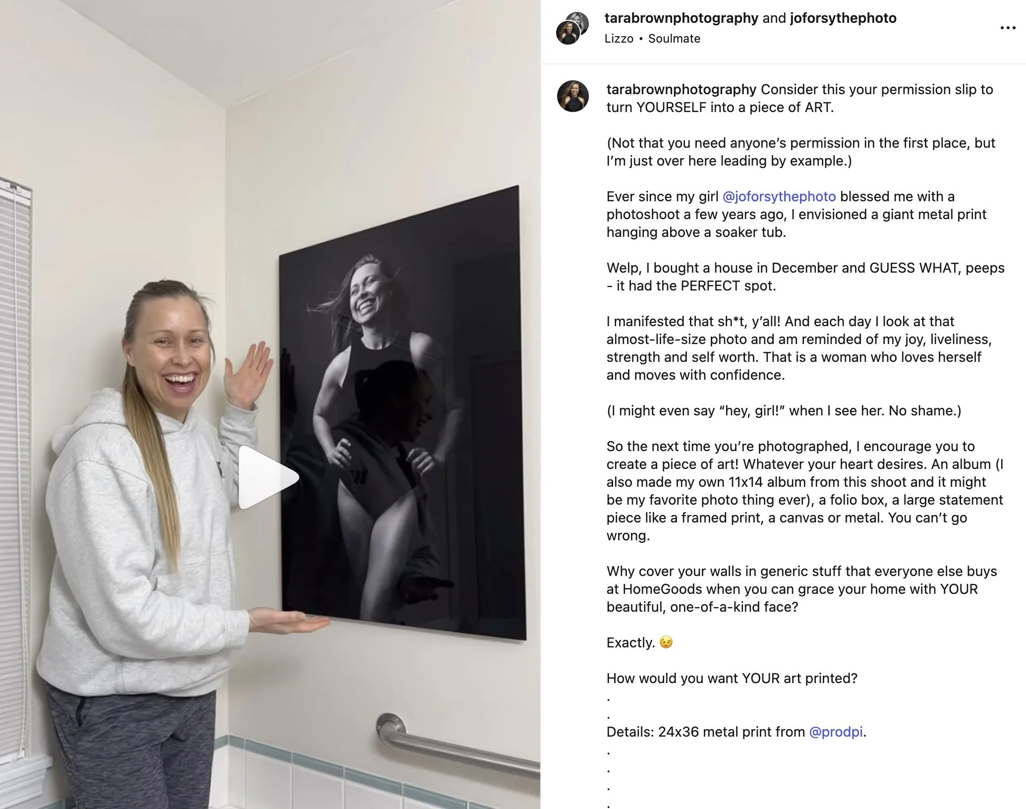 A woman smiling and pointing at a large black-and-white metal print of herself hanging on a white wall in a home or gallery setting.