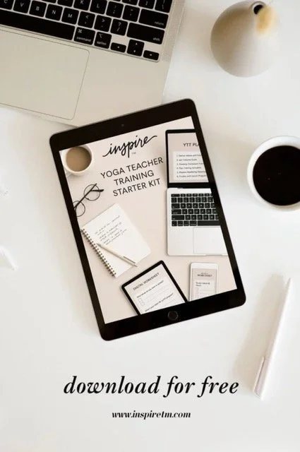 Tablet on a white desk displaying Inspire TM's 200 hour yoga teacher training starter kit with a notebook, e-reader, and smartphone. Surrounding items include a laptop, a white cup of coffee, a white vase, and a white pen.