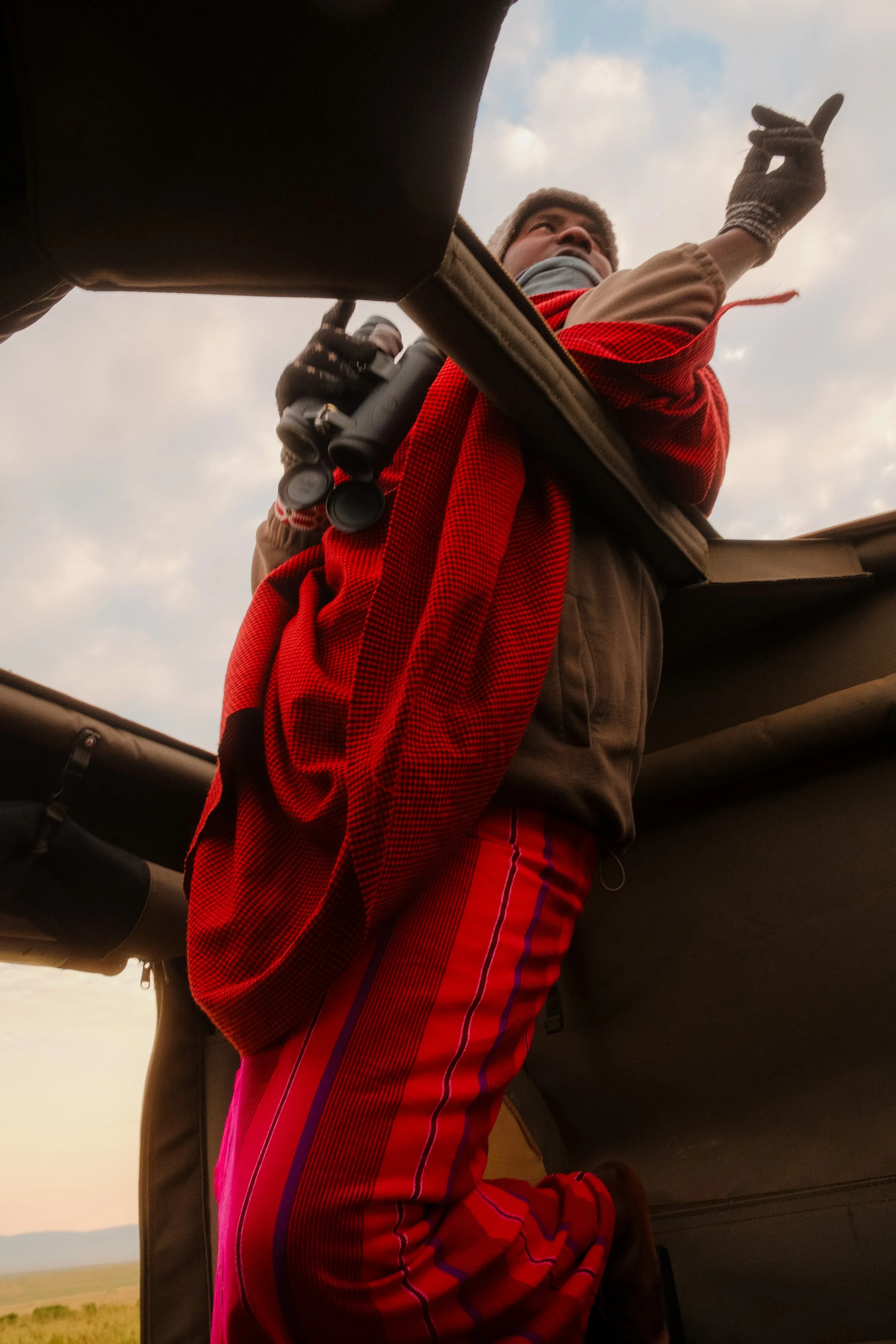 enkewa-safari-camp-masai-mara-kenya-maasai-guide-safari-vehicle-roof-binoculars-red-shuka-travel-photography-10.jpg