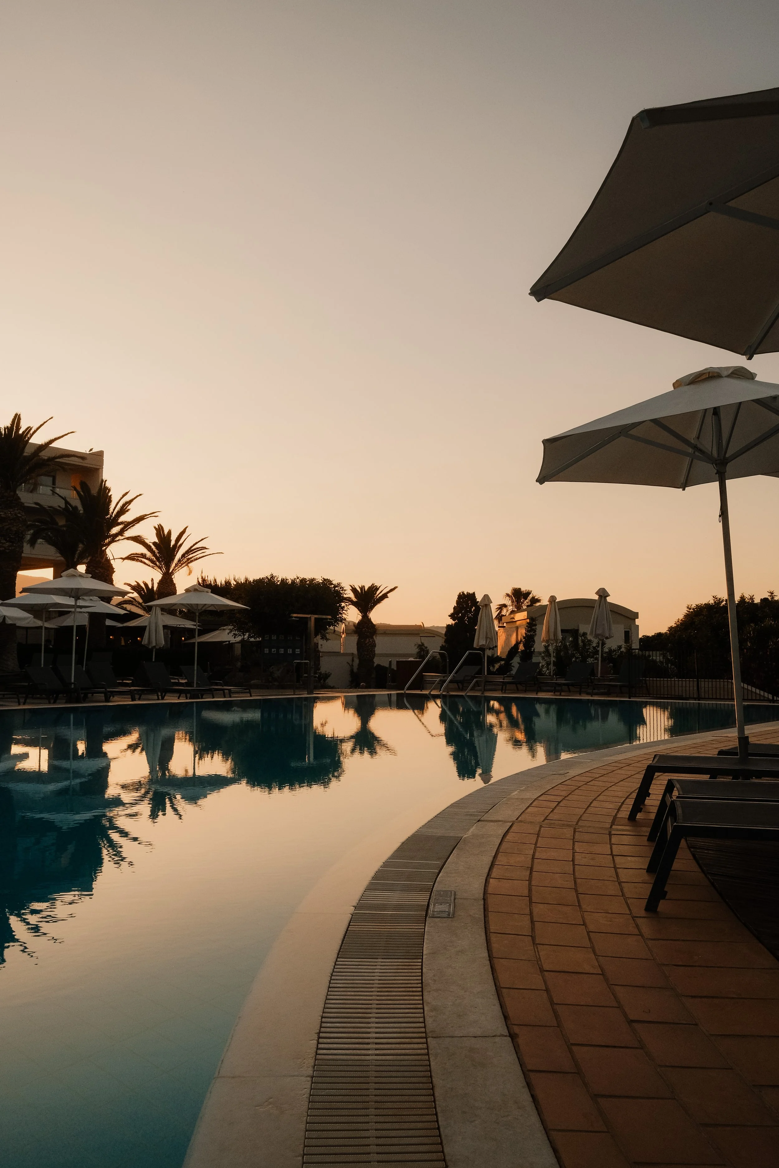 agapi-beach-resort-crete-greece-pool-white-umbrellas-lounge-chairs-sunset-reflection-panoramic-hospitality-photography-24.jpg