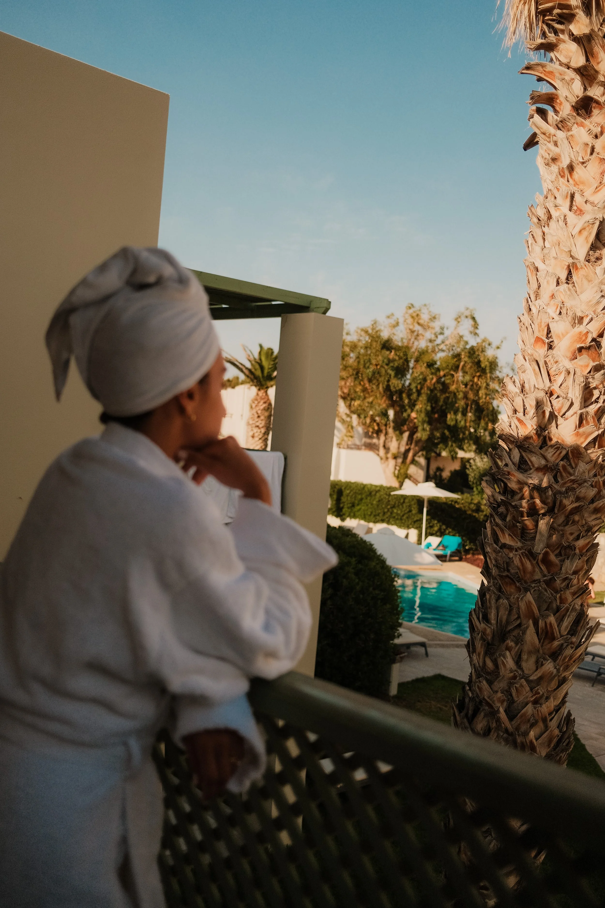 agapi-beach-resort-crete-greece-woman-bathrobe-balcony-pool-view-palm-tree-hospitality-photography-11.jpg