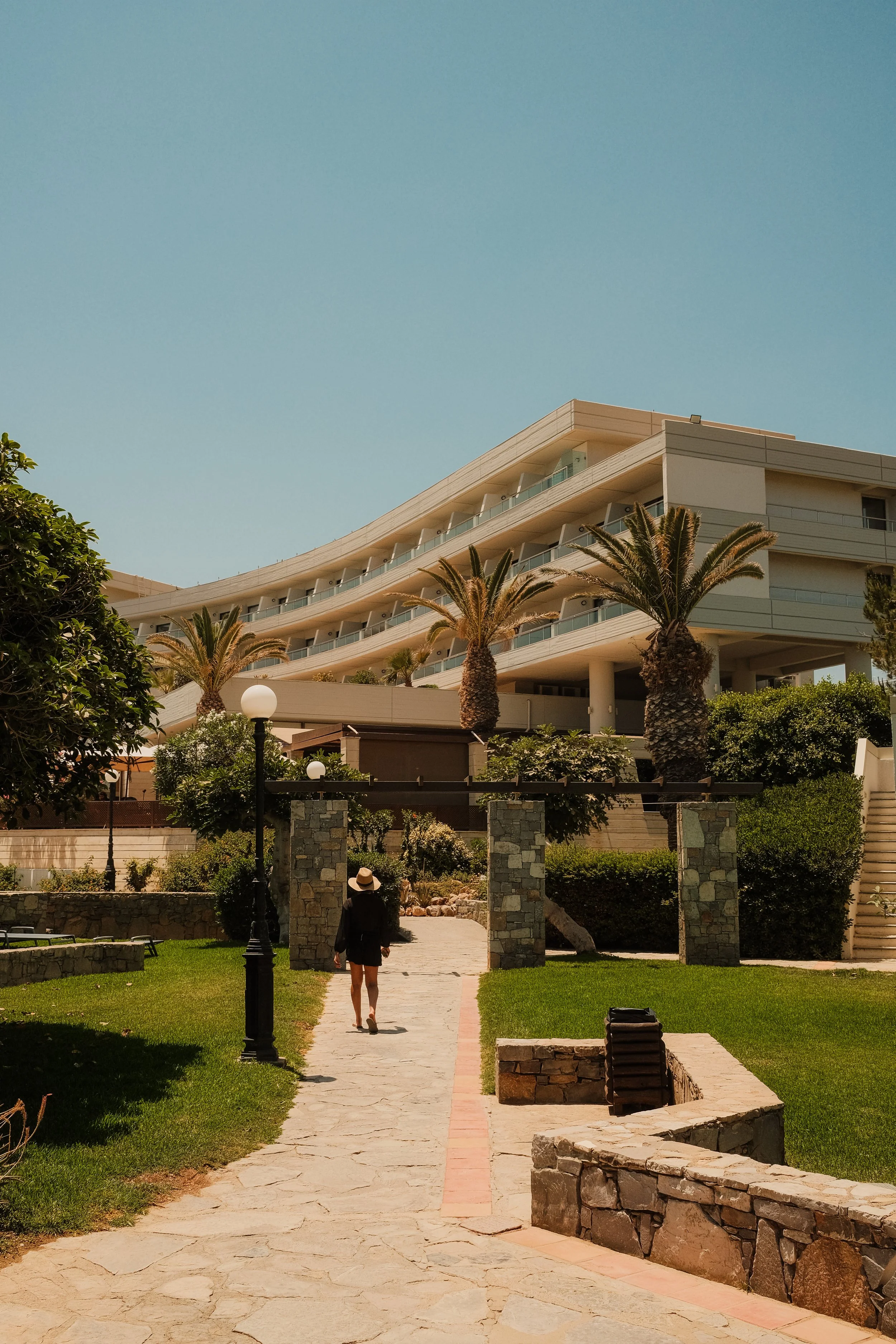 agapi-beach-resort-crete-greece-hotel-exterior-woman-garden-path-palm-trees-hospitality-photography-04.jpg