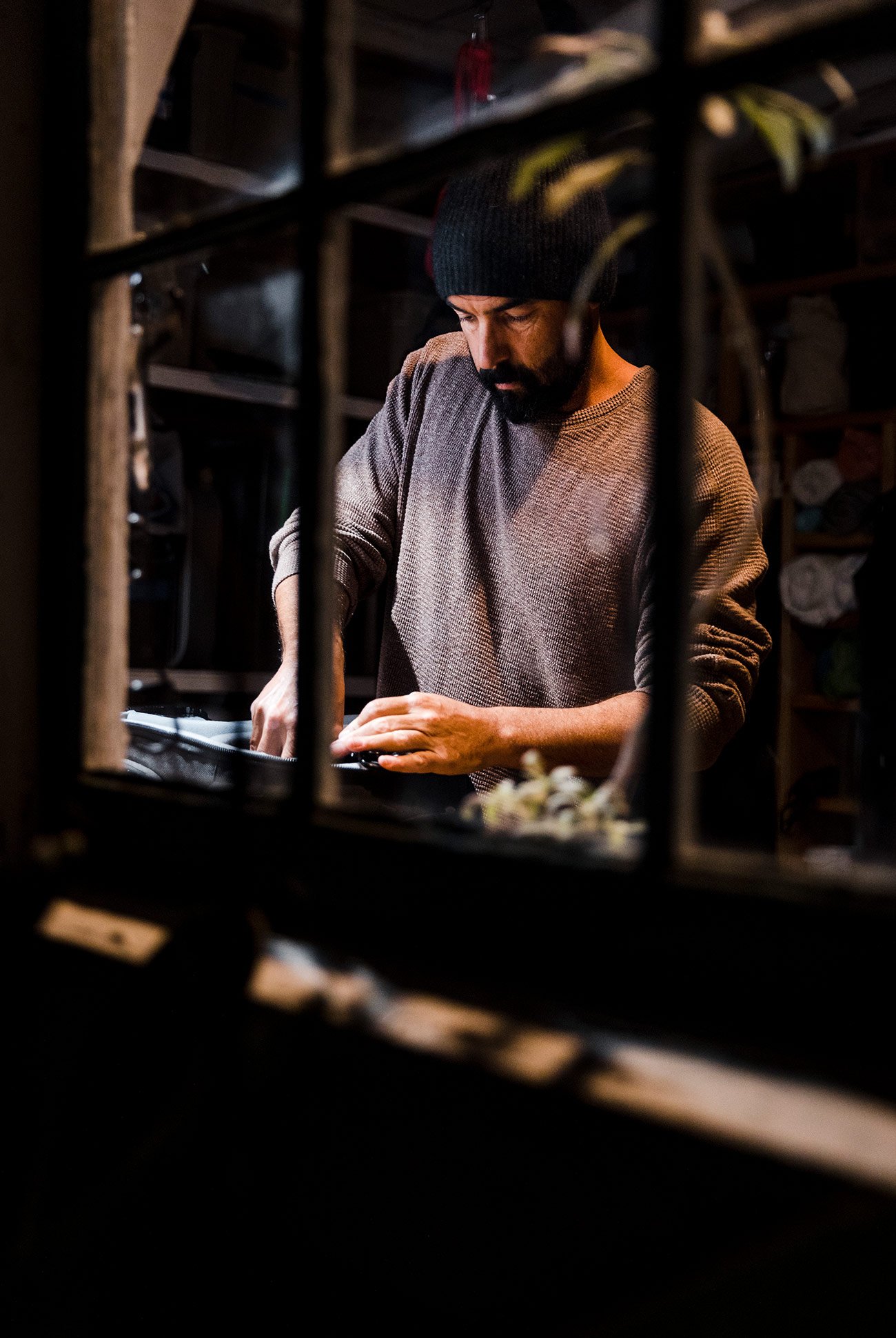 man wearing a beanie and preparing food in a kitchen