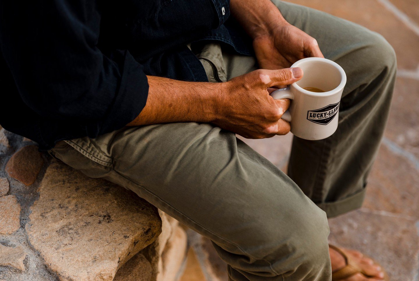 man holding coffee as he sits on stone steps