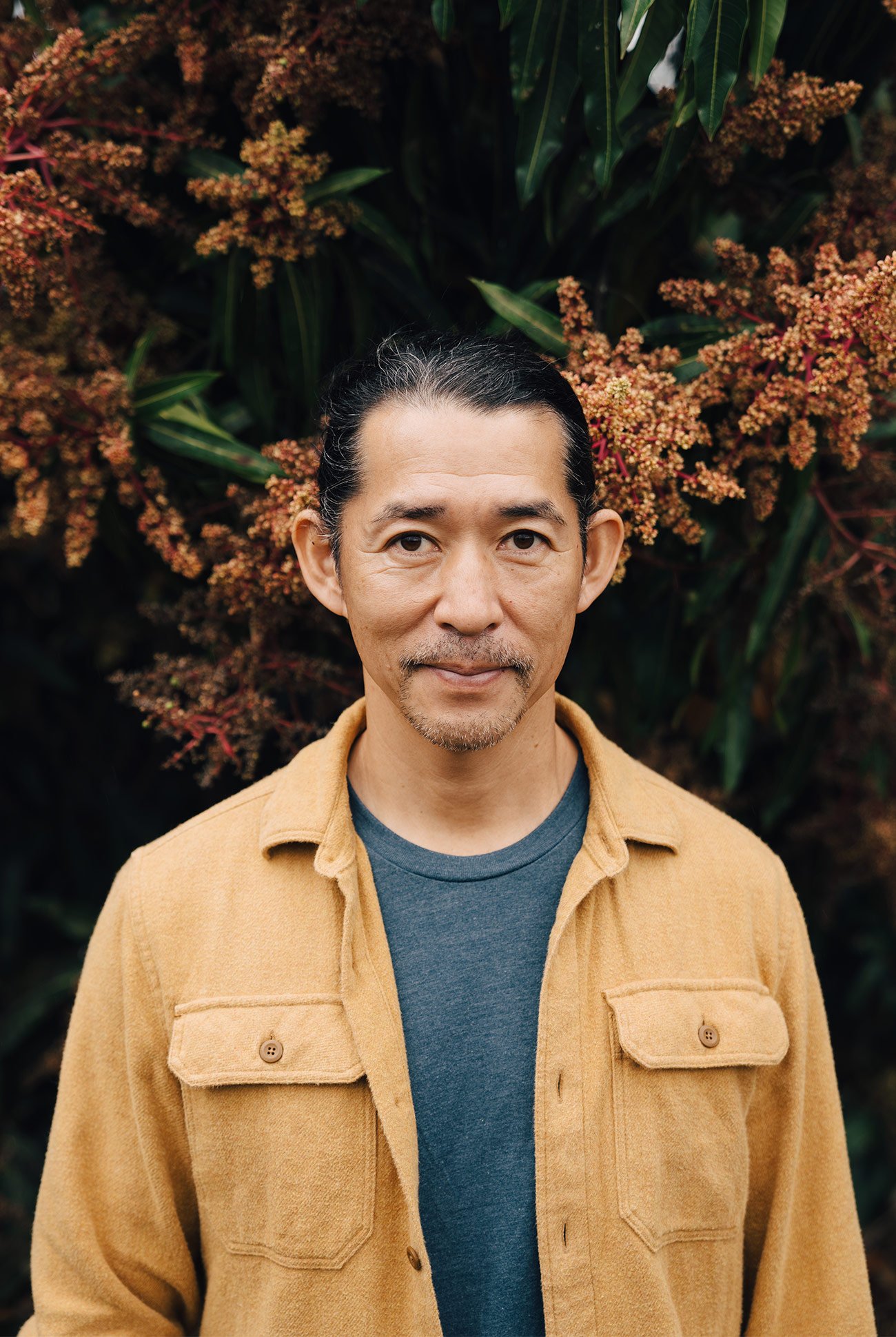 ken hirata staring at the camera wearing a light brown jacket