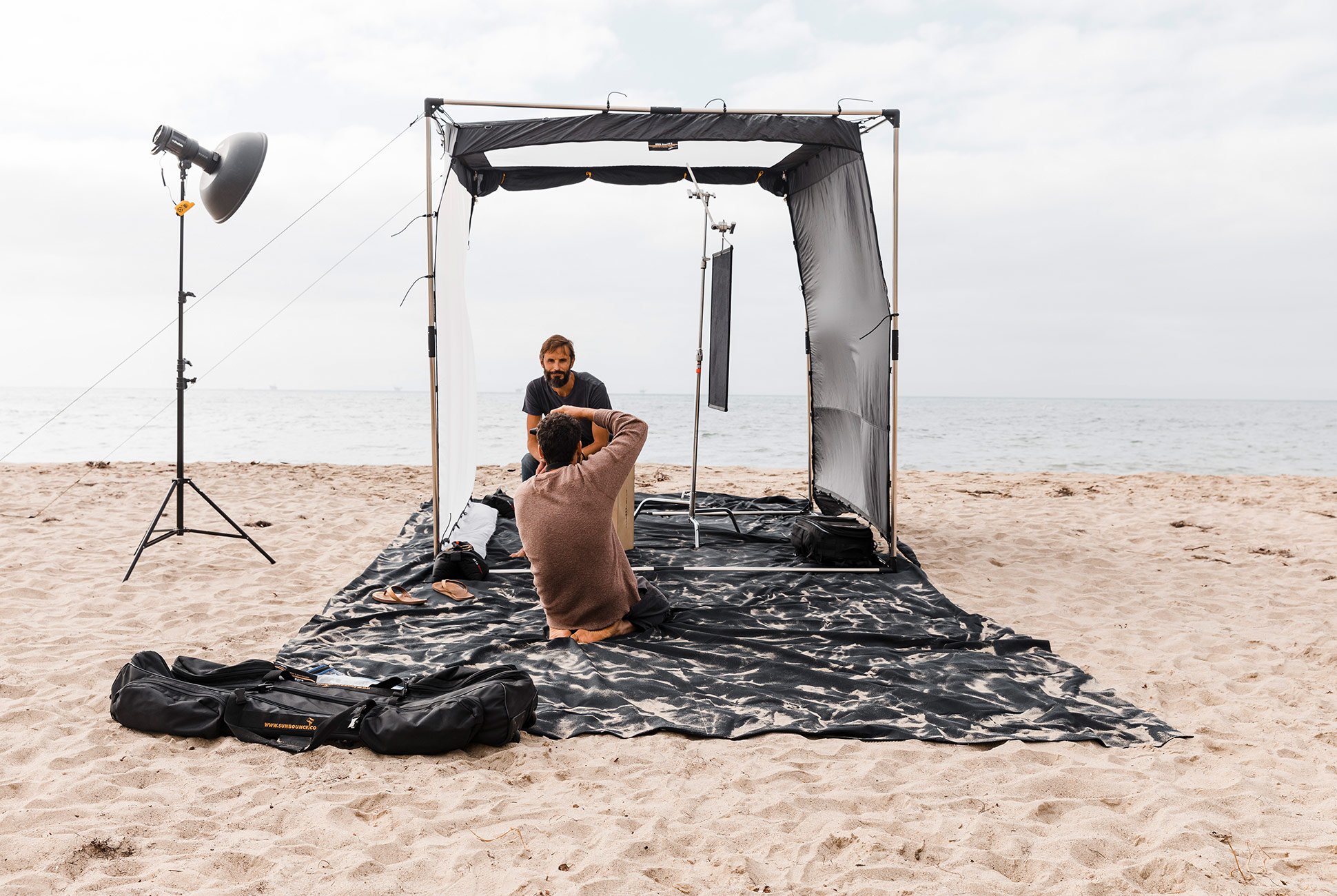 man setting up a photo backdrop on a sandy beach