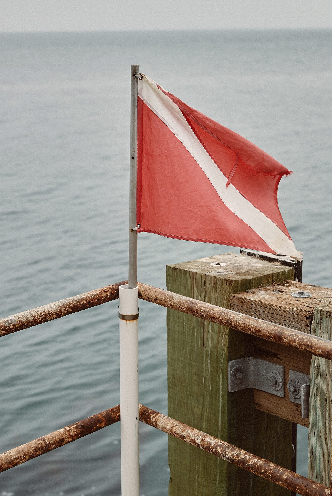 a white and red flag flying in front of the oean