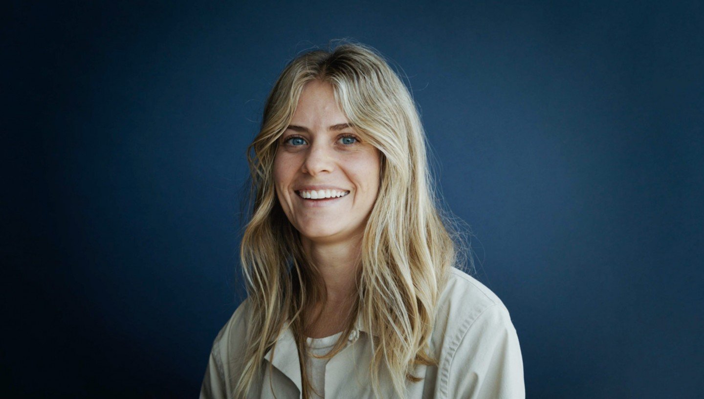 woman with blond hair and blue eyes smiling in front of the camera