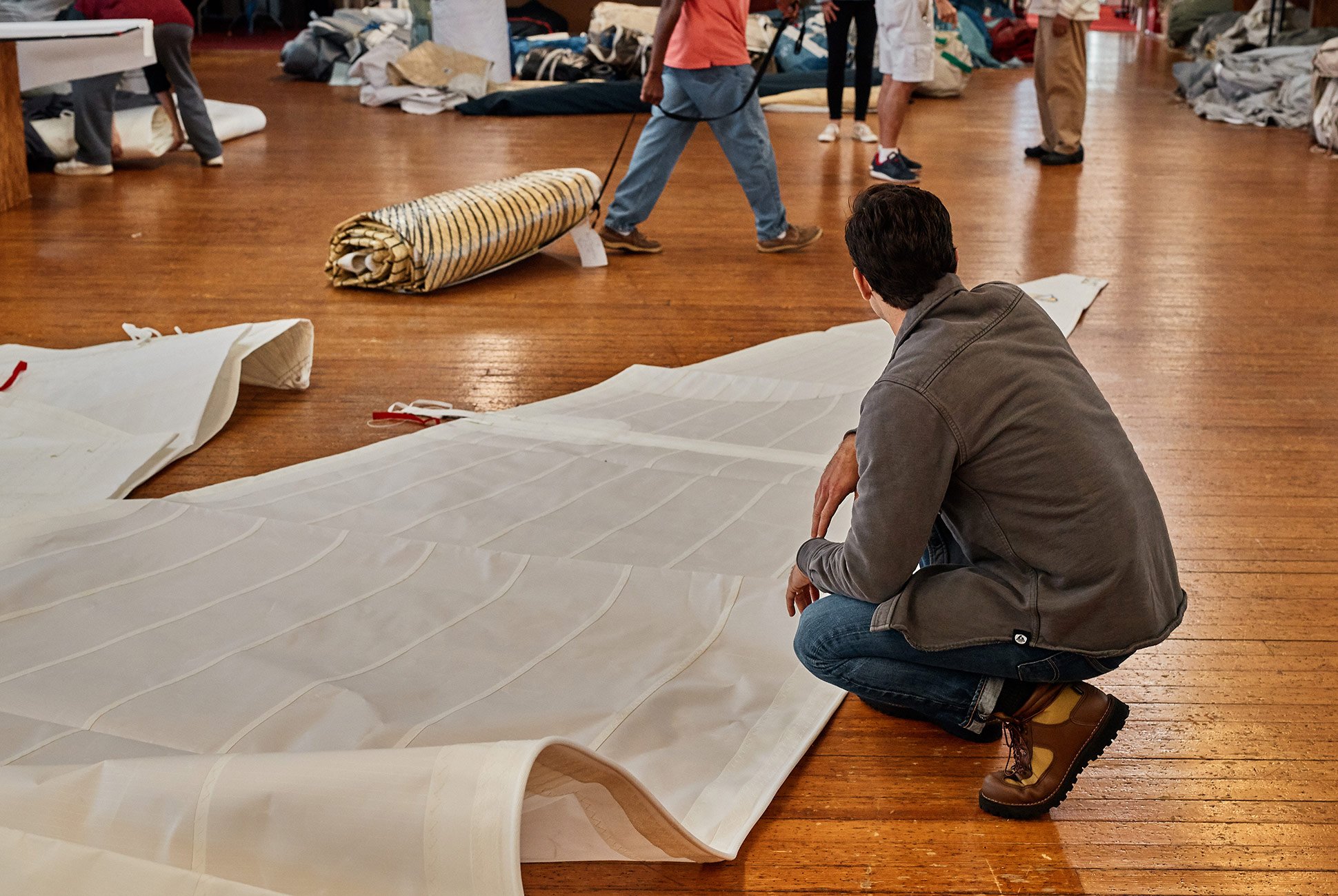 a large white piece of fabric unfurled on a floor while someone crouches down to look at it