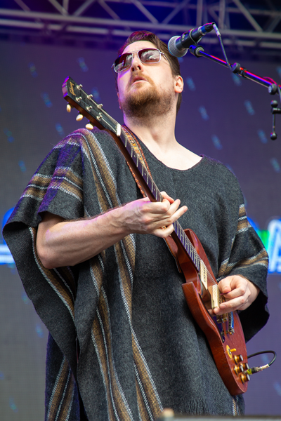 Brett Wood — Australian blues guitarist wearing sunglasses performing on stage with electric guitar and microphone