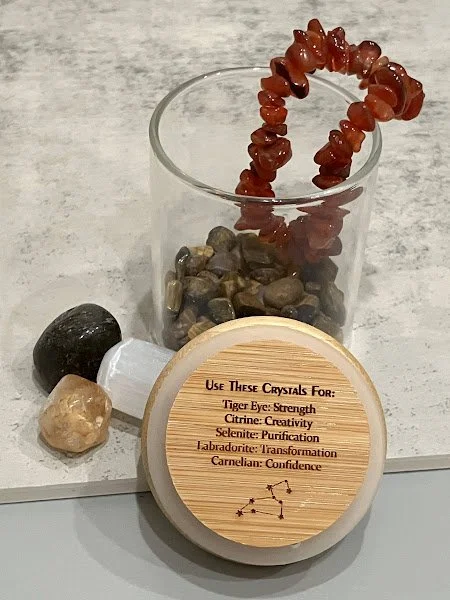 Contents of Zodiac Crystal Kit: Crystal Chips, Tumble Stones, Chip Bracelet, Storage Jar w/ Illustration of Constellation- Pictured LEO ($22)