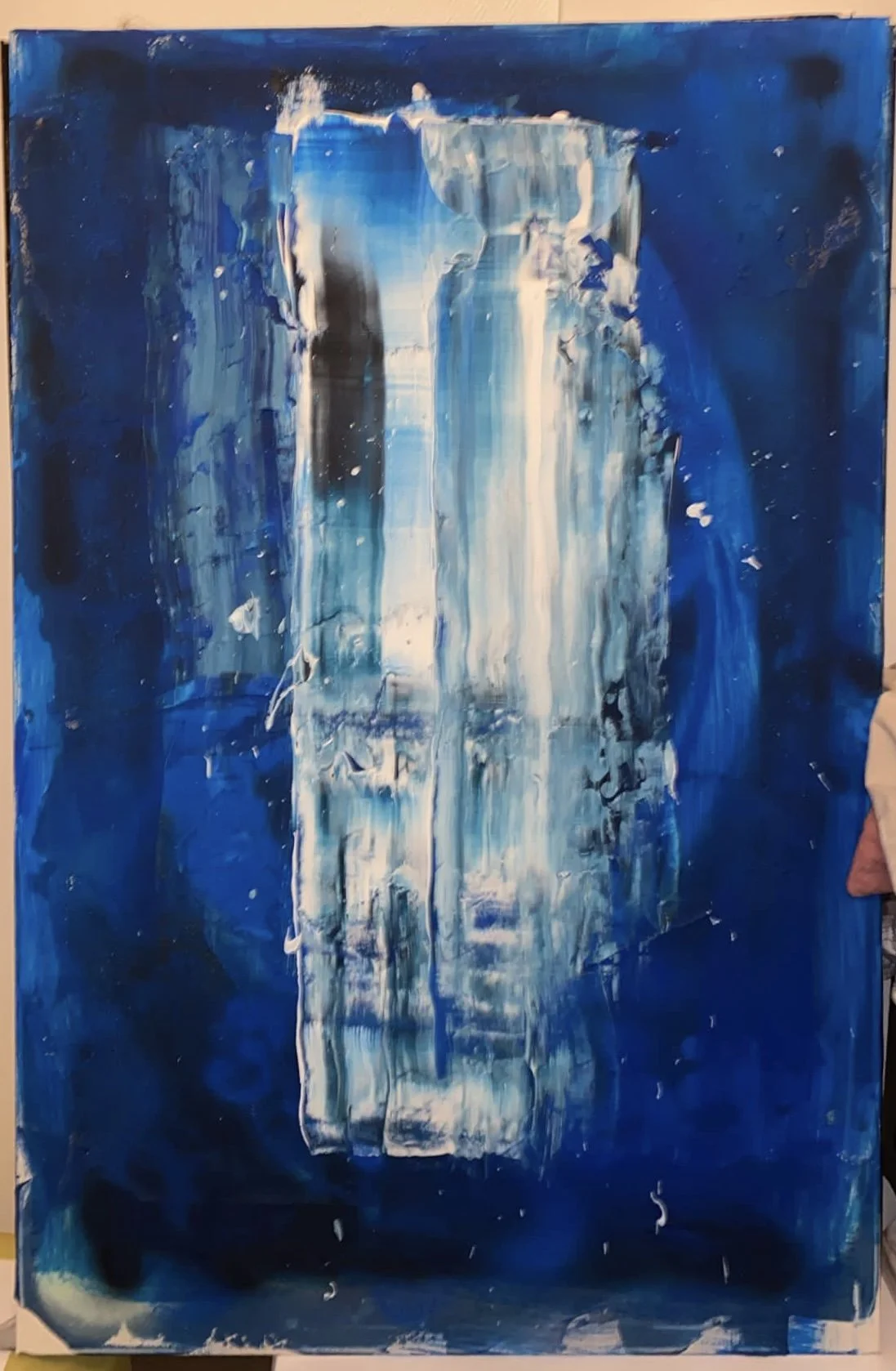 Abstract painting with vertical streaks of white, beige, and blue on a dark blue background.