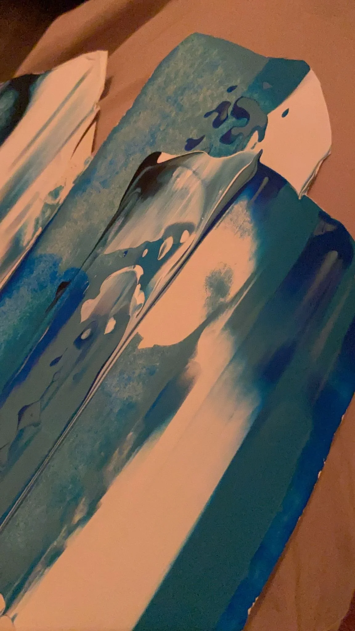 Close-up of a painted wooden sculpture of a whale, with beach and cloud scenery painted on its surface.