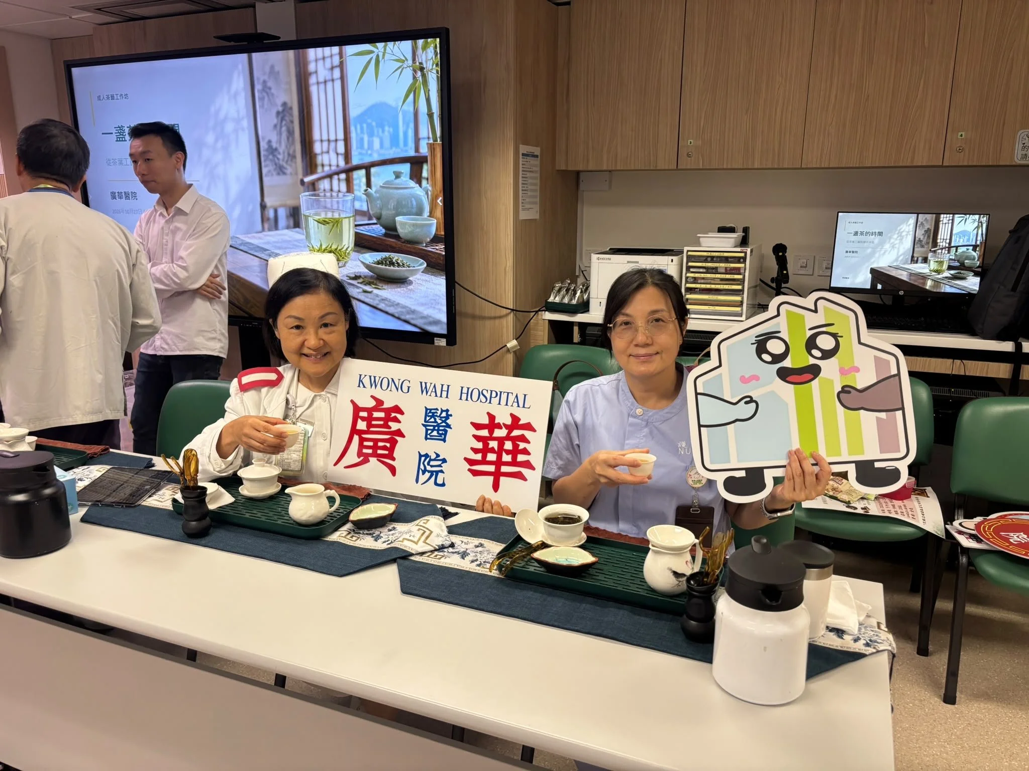 兩位參加者在茶席前手持廣華醫院拍照道具留影