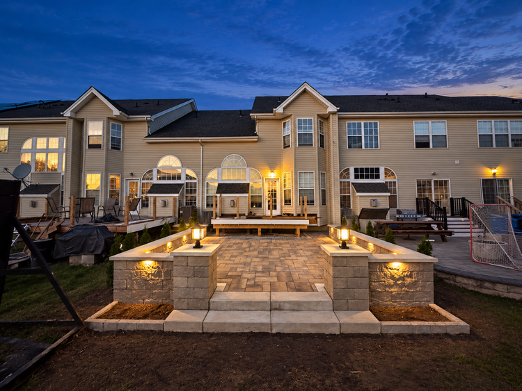 Techo-Bloc paver patio with lit retaining walls and Raffinato steps at dusk
