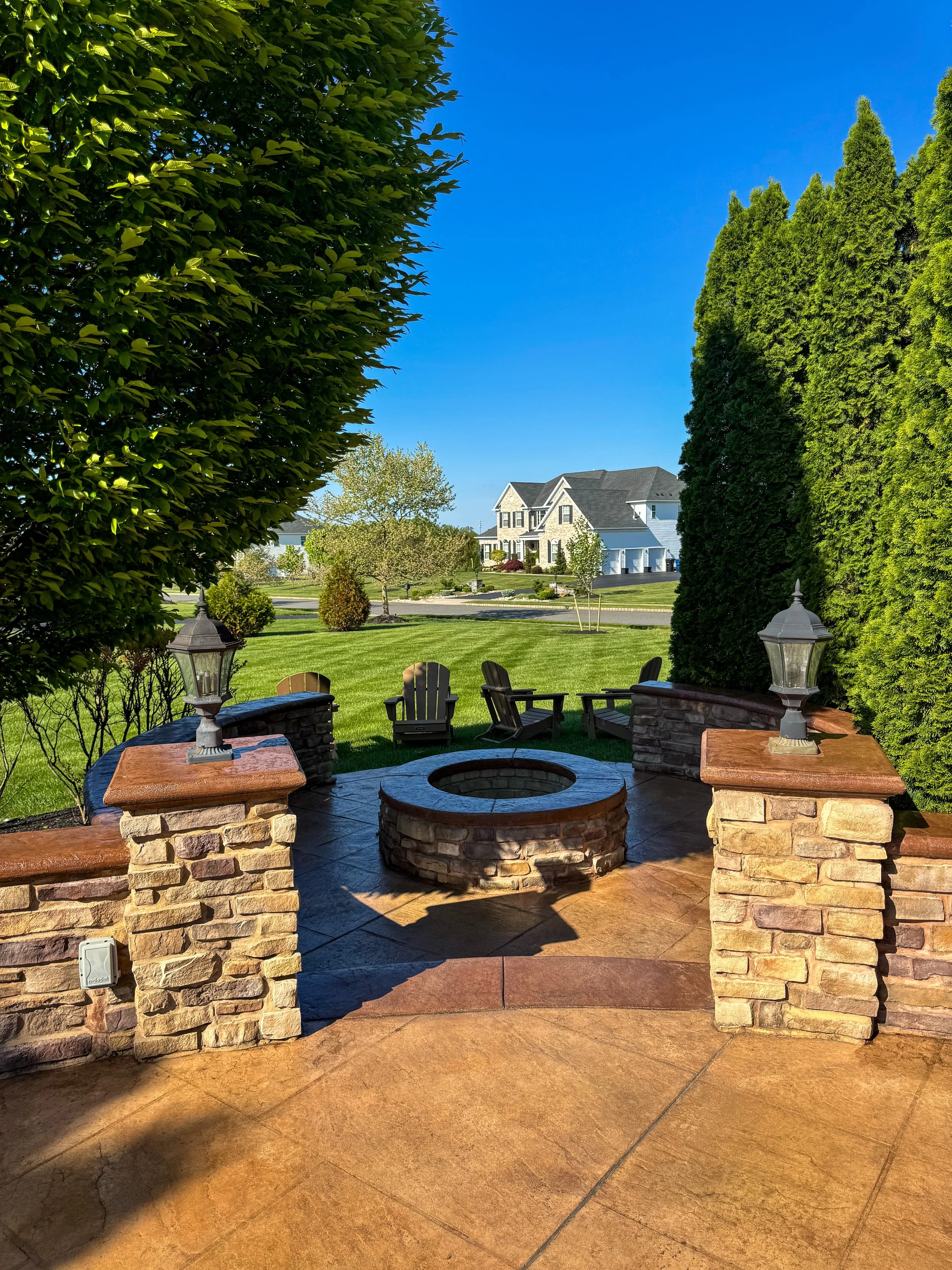 Desert tan stamped concrete walkway with stacked stone veneer pillar and cap light in South Jersey