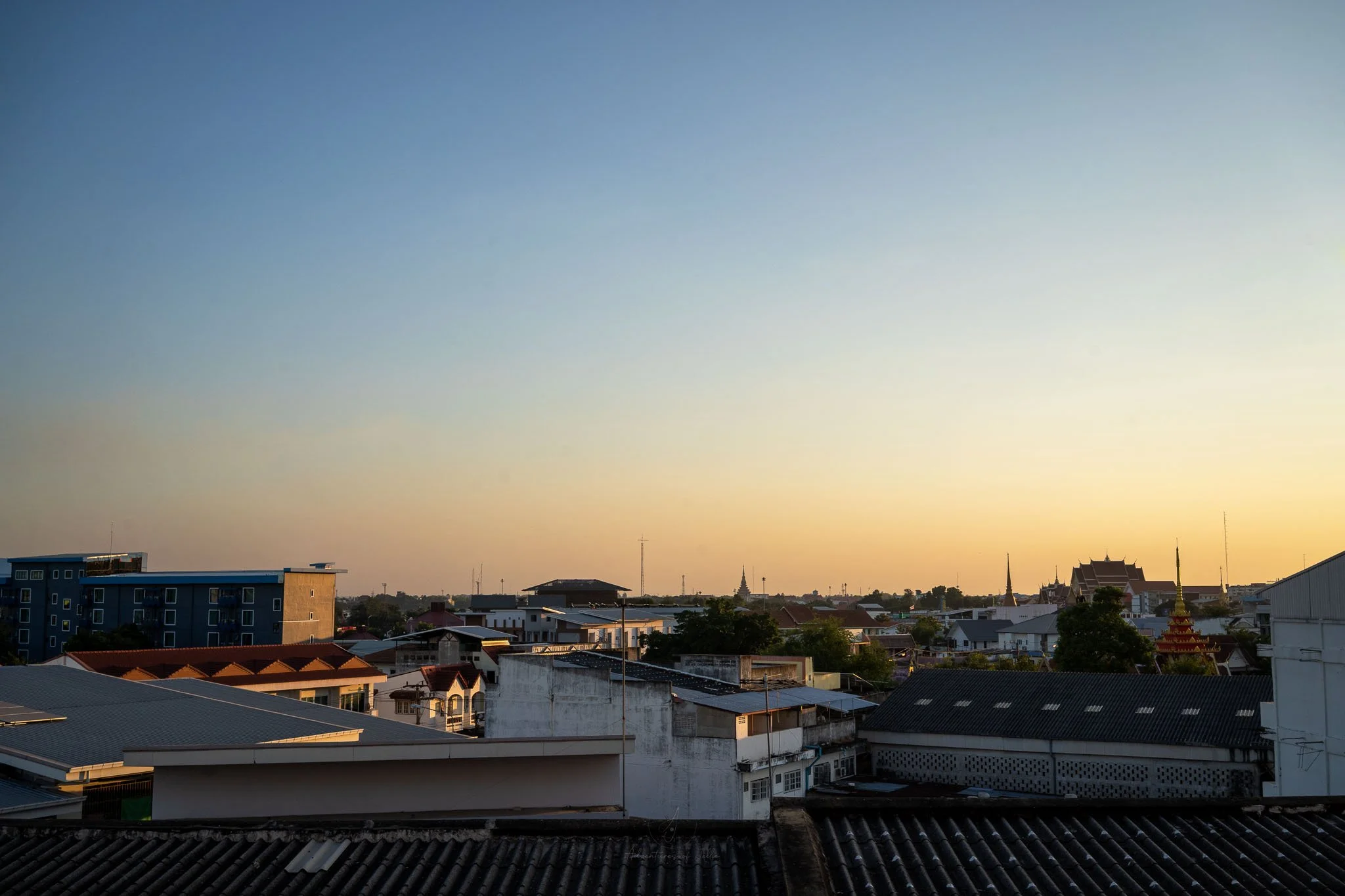 A sunset view over the rooftops and temples of Khon Kaen. The photo was taken from the balcony of a private room at the Neo Hotel.