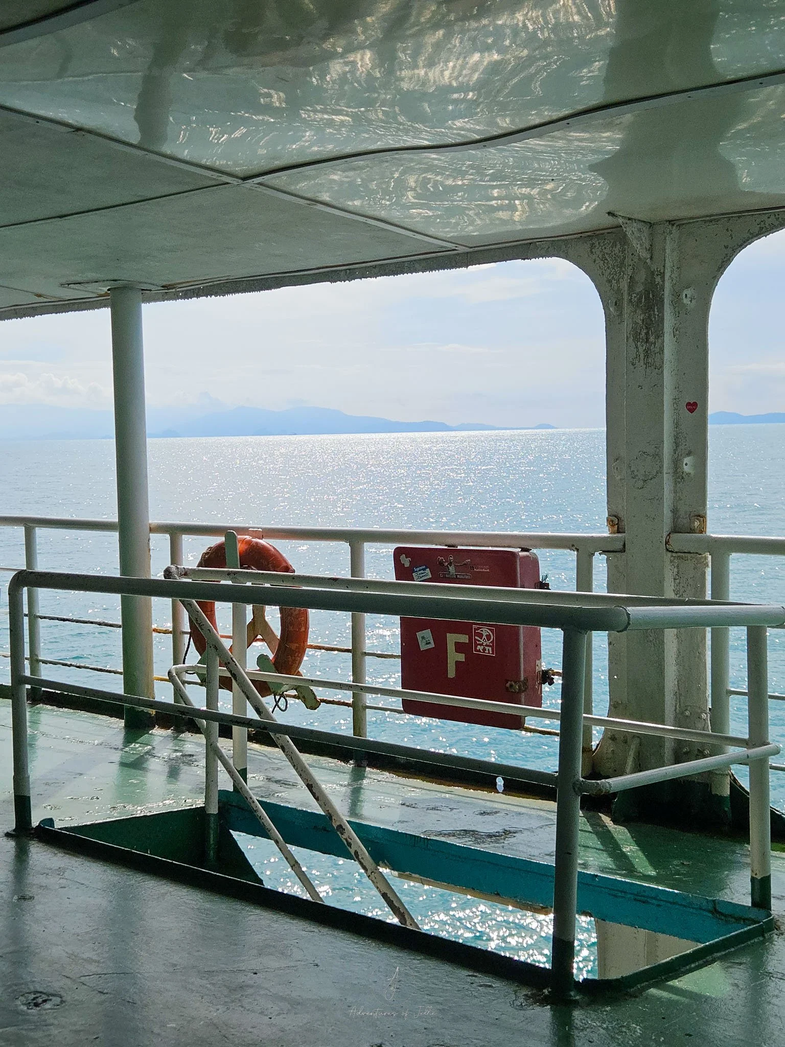 A view out to sea taken from the deck of the Raja seaferry from Donsak Pier to Koh Phangan. Next to the stairwell is an orange life ring and a firehose.