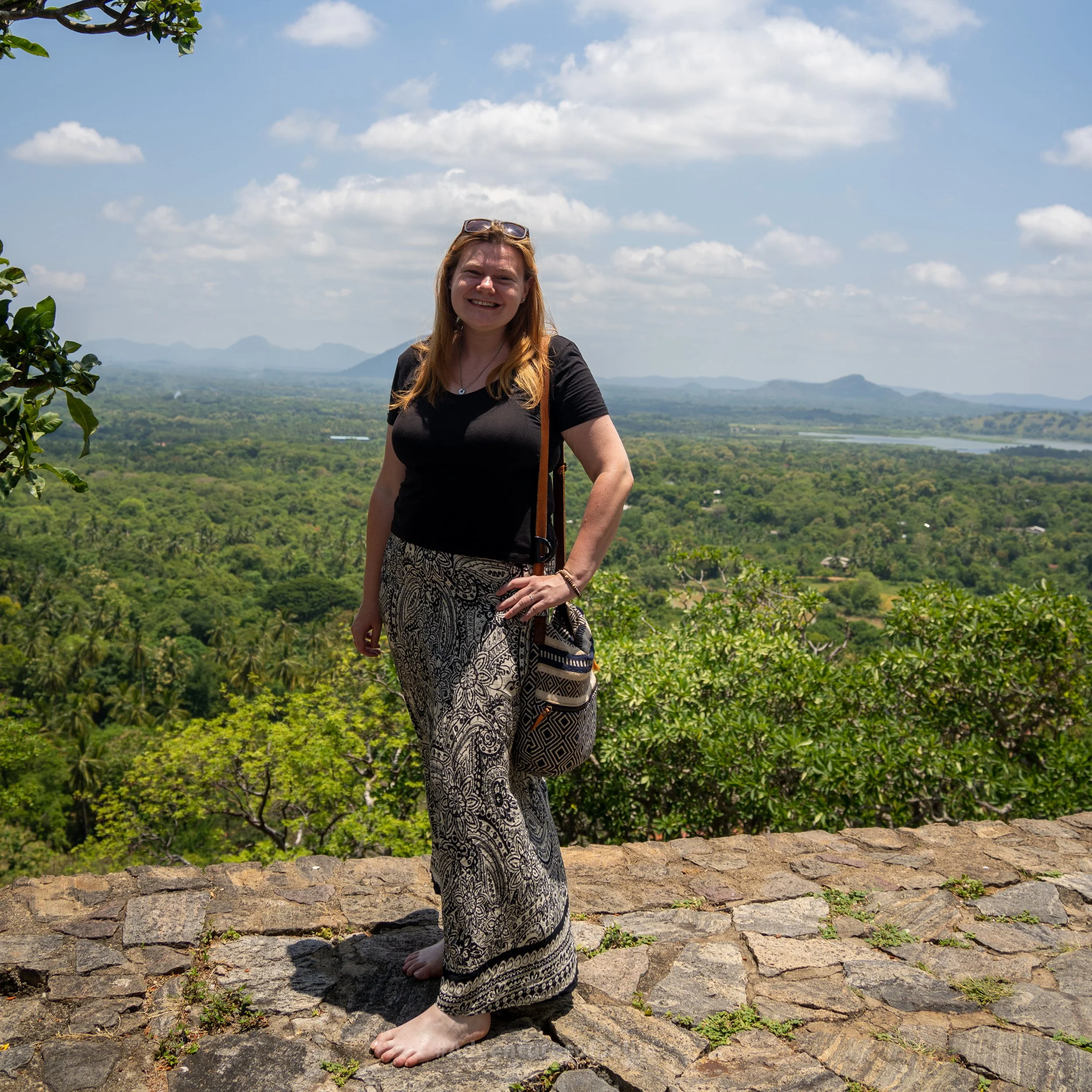 Ellie poses on a ledge overlooking a sweeping vista outside of Dambulla Royal Cave Temple