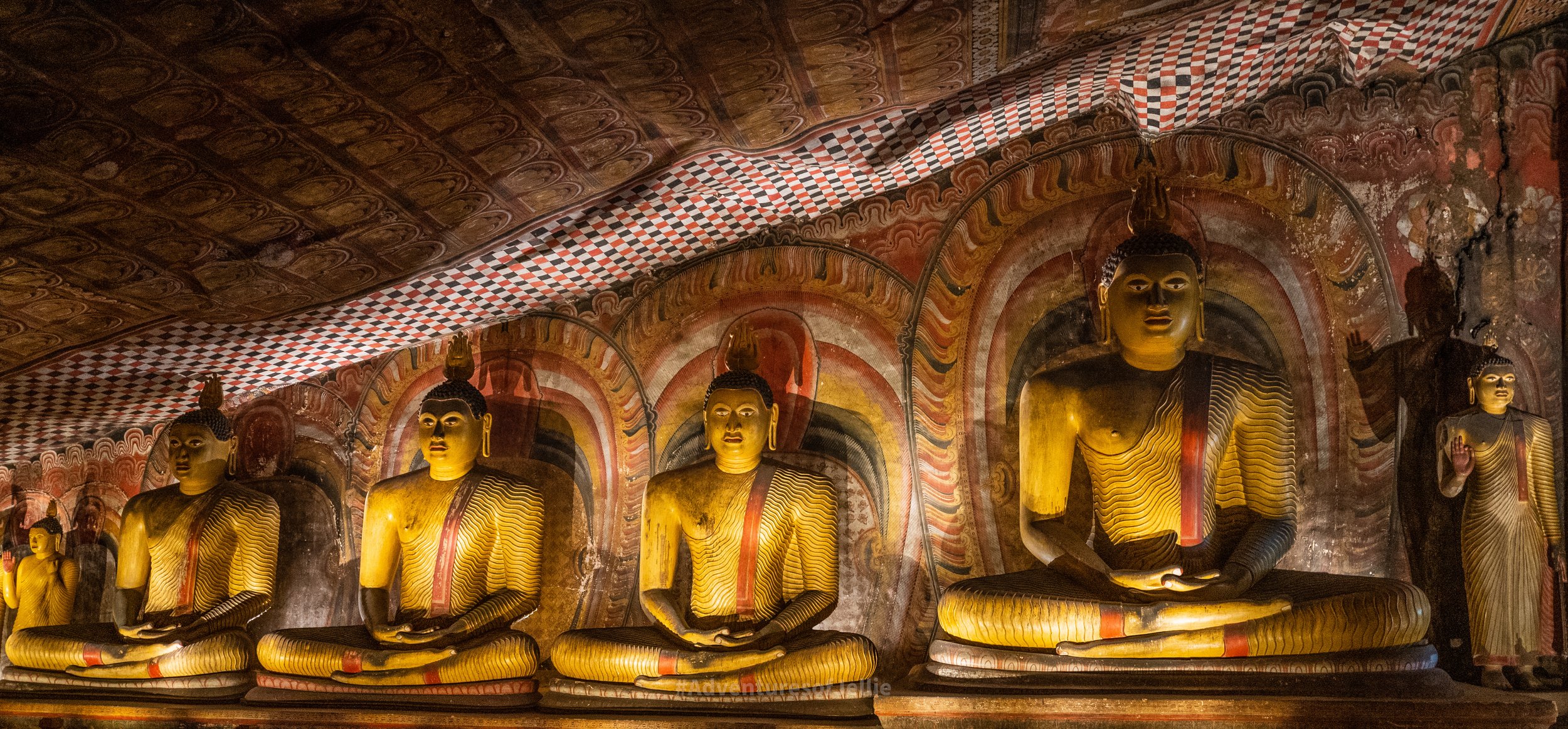 A row of Buddha statues, each larger than the last, line a cave wall at the Dambulla Royal Cave Temple