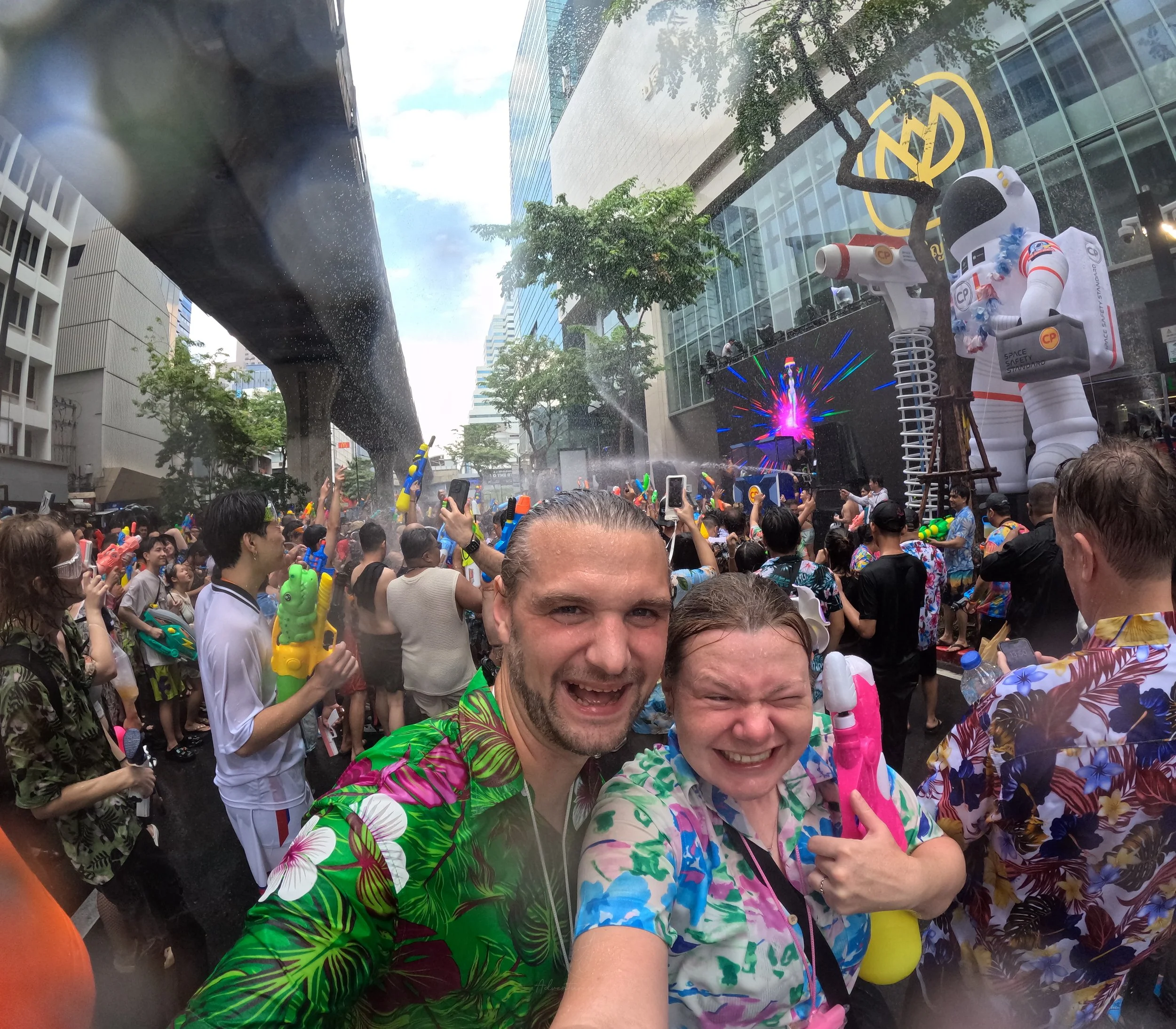 Adventures of Jellie pose for a selfie wearing colourful printed shirts in the middle of the Songkran celebrations in Thailand. In her left arm Ellie is holding a pink, white and yellow water pistol.