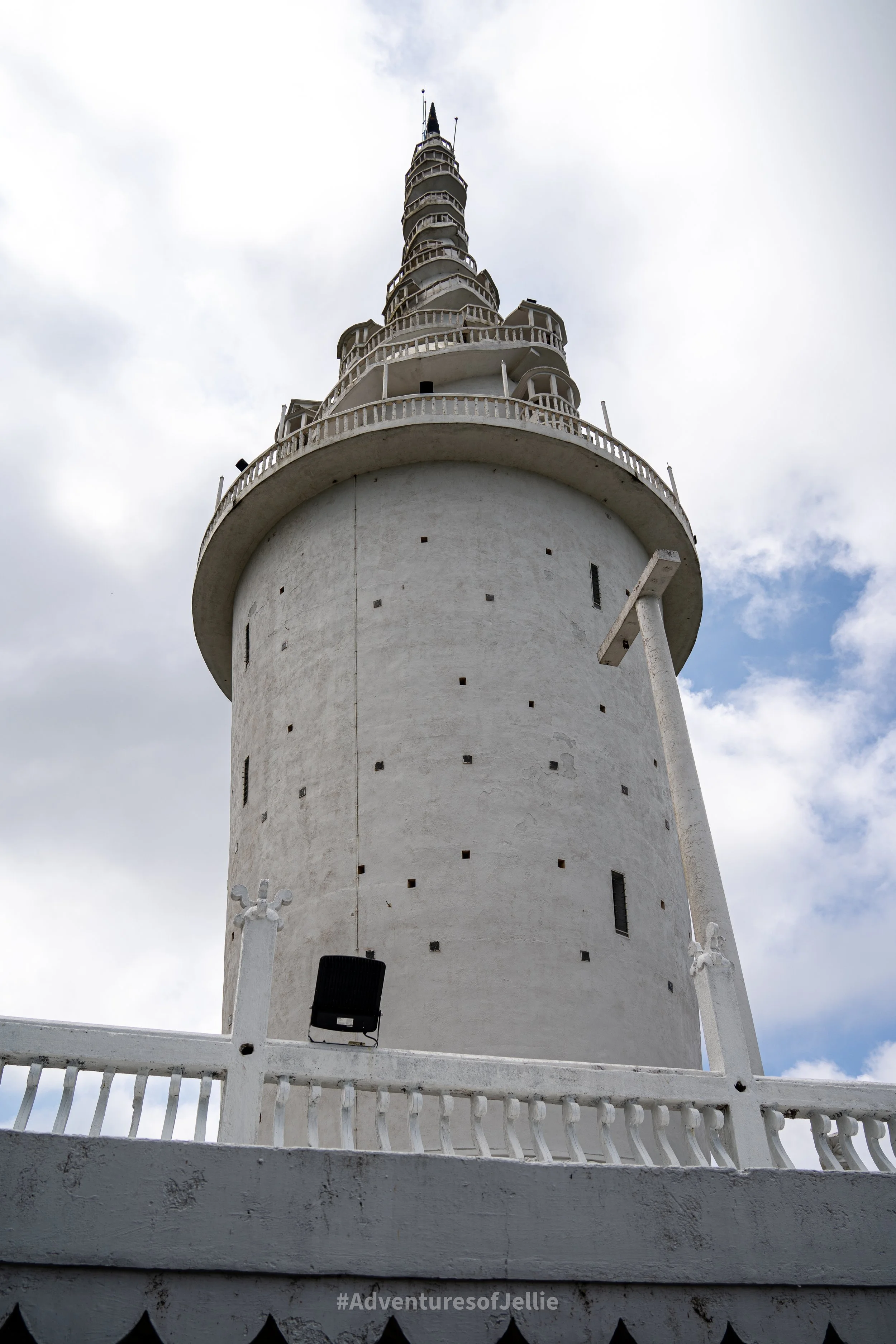 Standing tall, the Ambuluwawa Tower of Gampola Sri Lanka. A splayed white conical building with a spiralling staircase leading to the towers rooftop point.