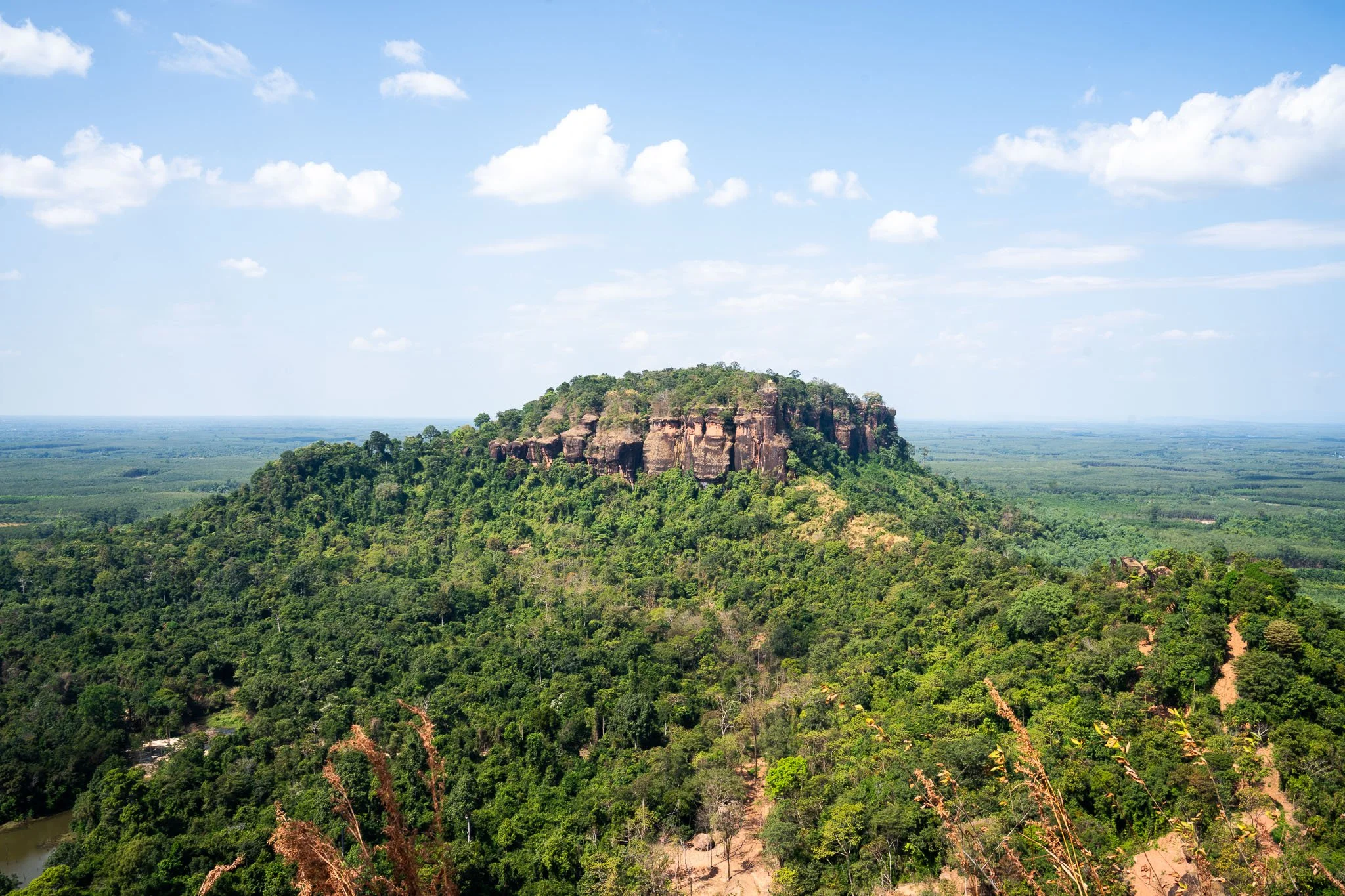 A rock formation rises from the isan forests. It is seen from the vantage point above - the summit of Wat Phu Tok