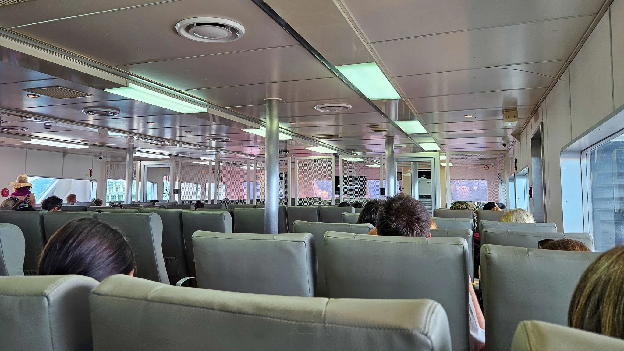 Passengers onboard the Seatran ferry from Koh Phangan to Surat Thani sit facing forward in rows upon rows of grey leather seats.