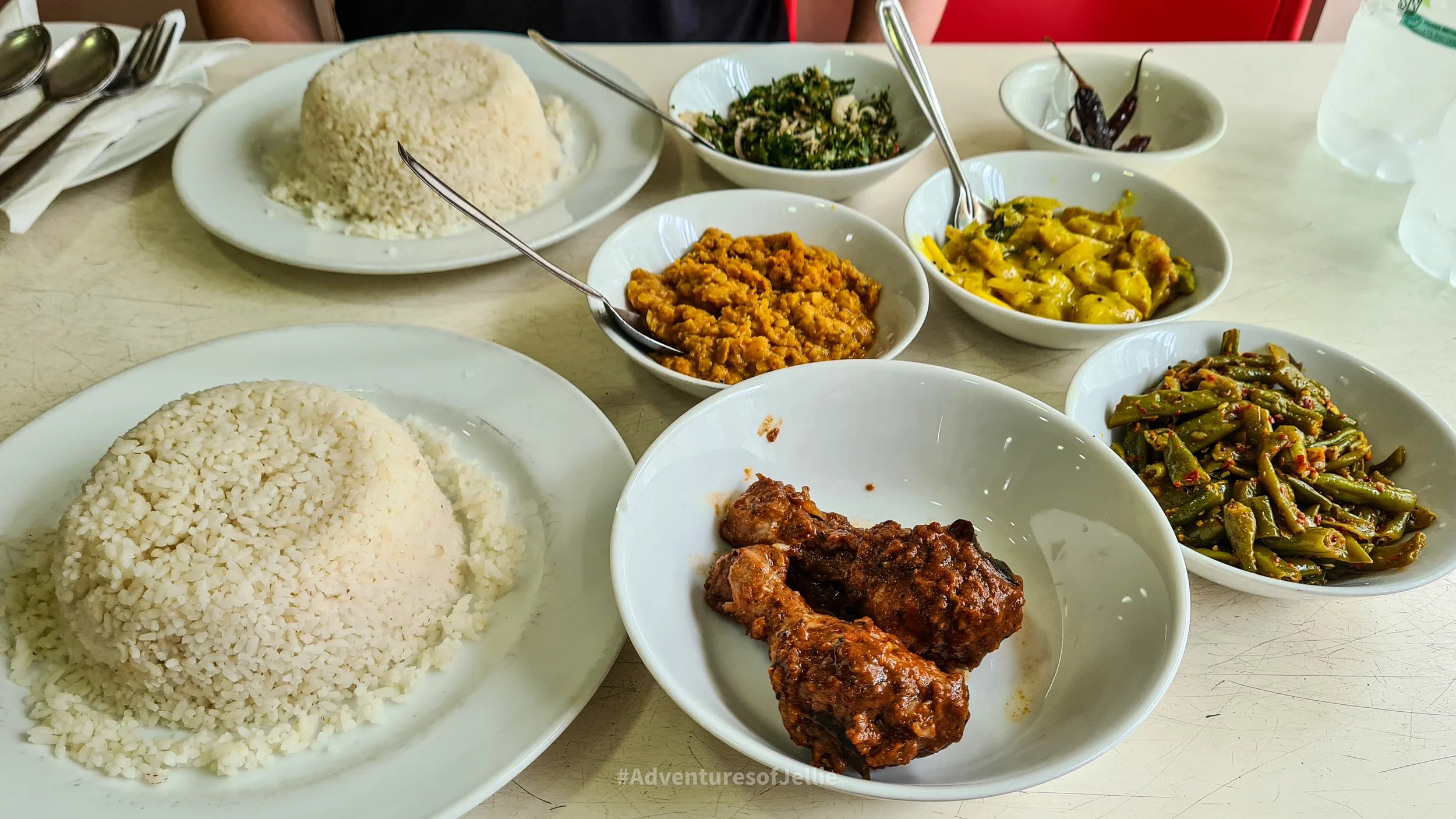 A mountain of rice is served with four vegetable curries, chicken drumsticks and roasted chillis. Traditional rice and curry found at Siri Ramya Hotel in Kandy Sri Lanka.