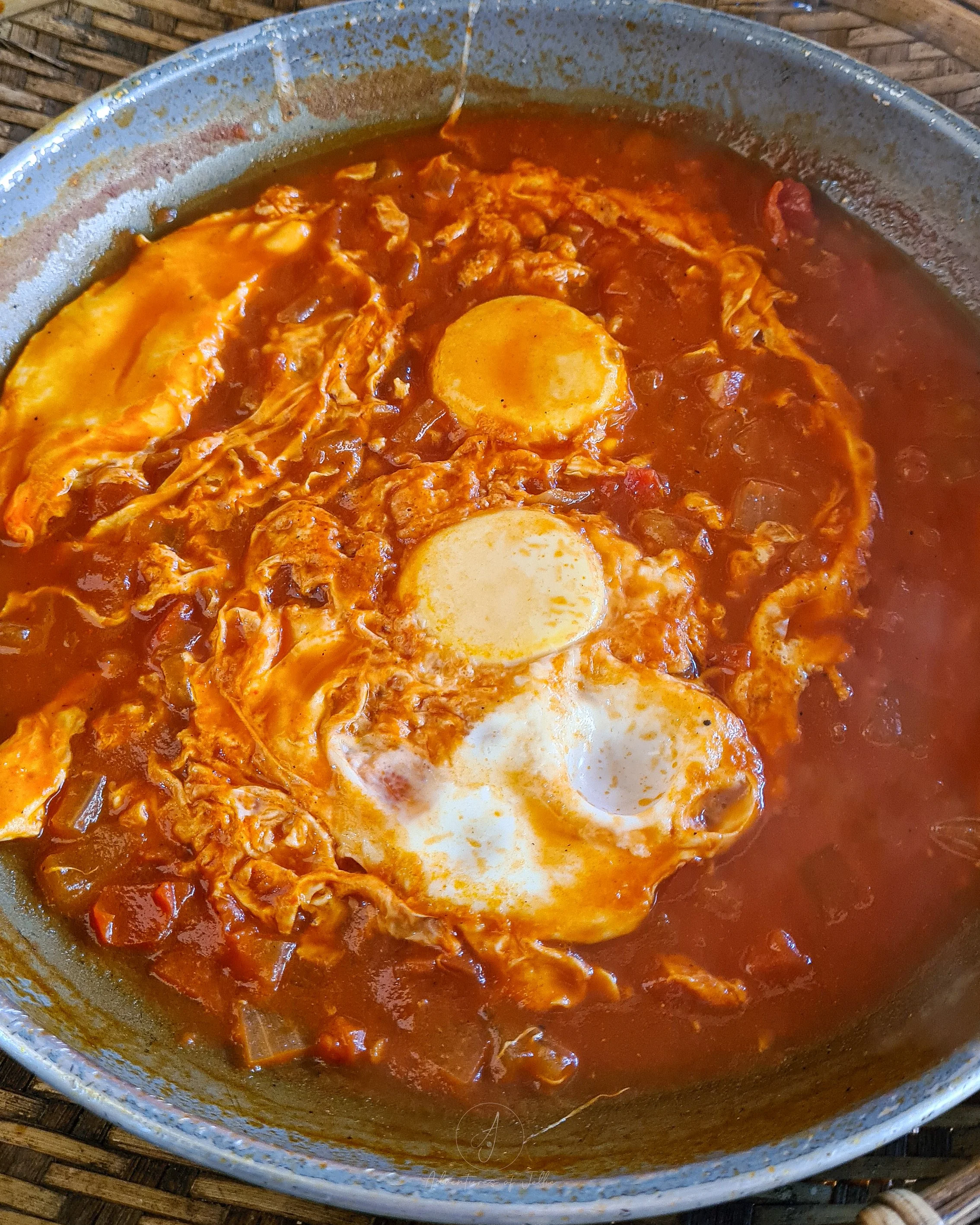 A metal pan is filled with shakshuka and two fried eggs at the Couleur Cafe of Nong Khiaw in Laos.