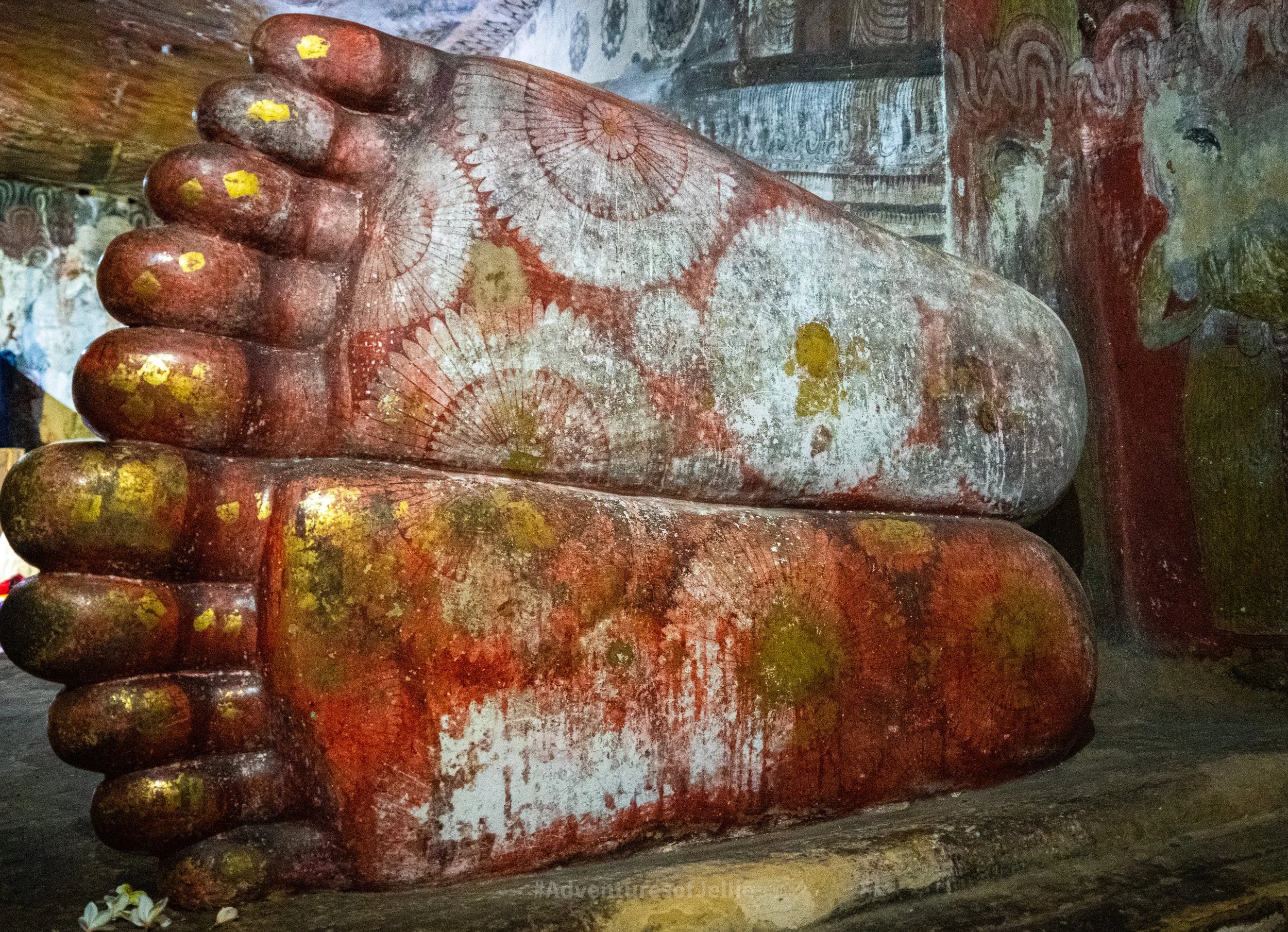 The large soles of the reclining Buddha in the 1st cave of the Royal temple. The feet are dyed red with whirls and geometric patterns painted on. Across the toes and soles are patches of gold leaf left by devotees.
