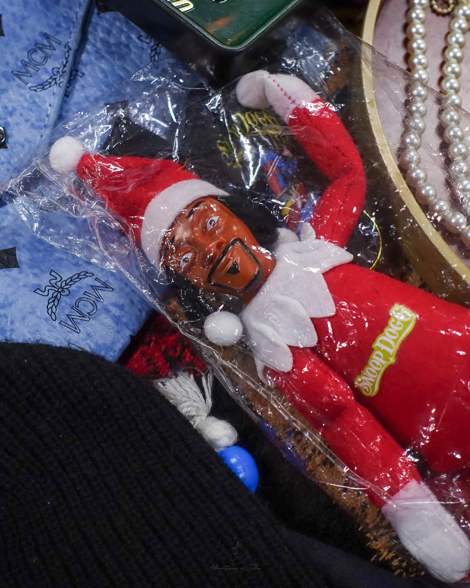 A Snoop Dog Father Christmas doll sits in clear plastic wrap on a market stall table at the vintage Re:Turn Market of Bangkok.