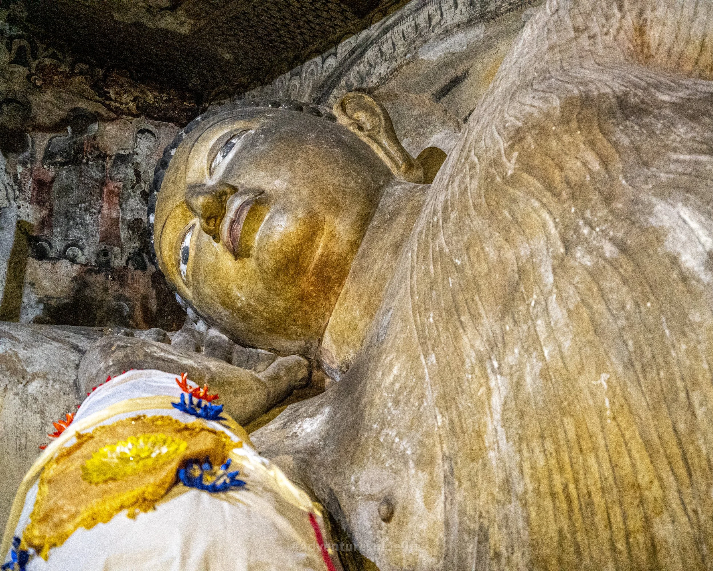 A reclining Buddha lies in a colourfully painted cave at the Dambulla Royal Cave Temple
