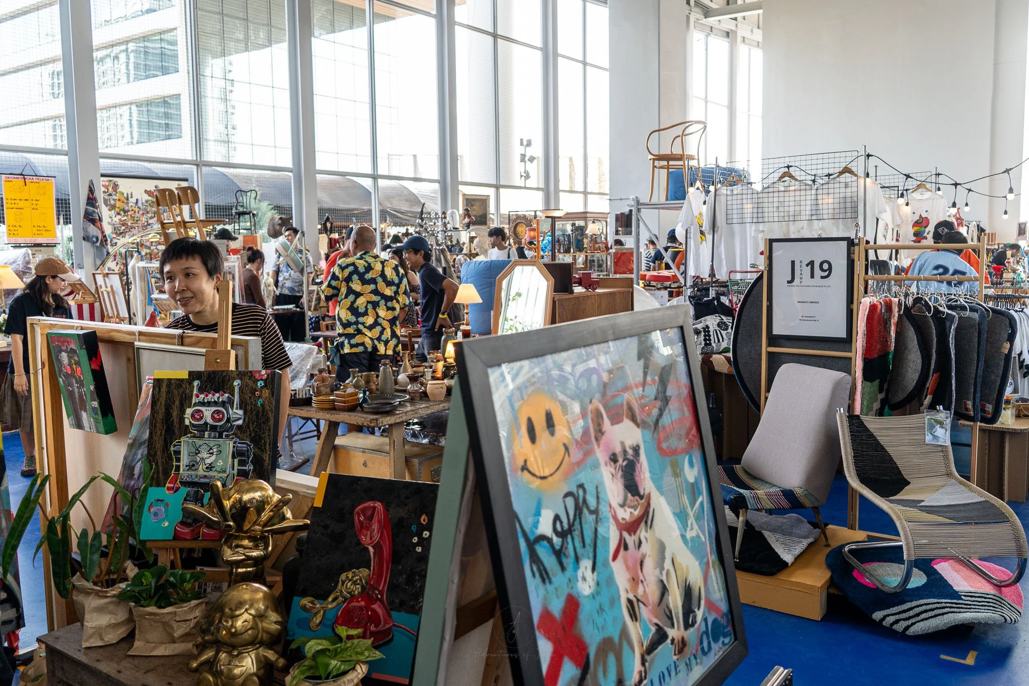 Market stalls at the Made By Legacy Flea Market stretch away from the viewer. The stalls are selling everything from vintage clothes, paintings, chairs and antiques.
