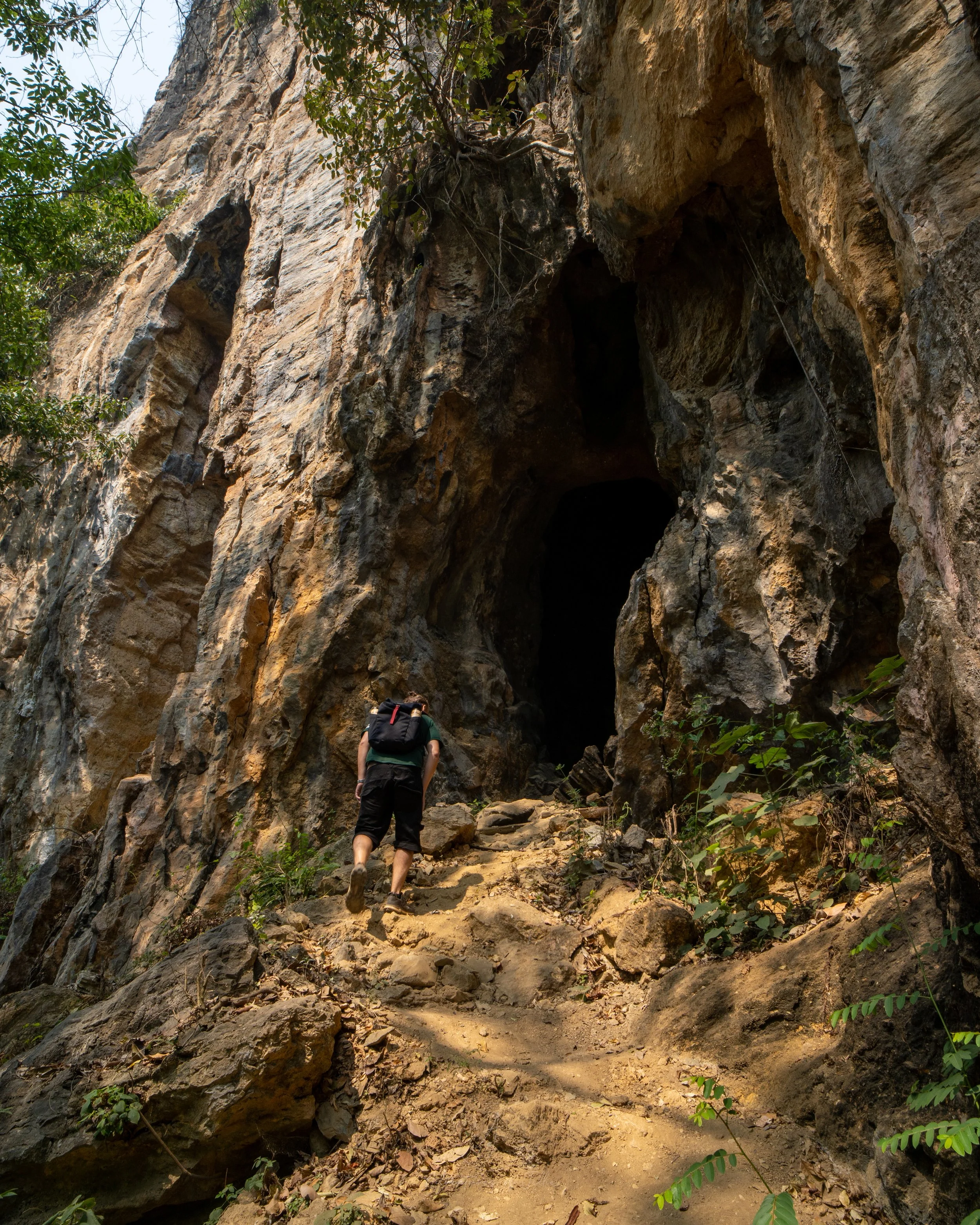 John walks up a dusty path to the pitch black cave entrance of the Pha Kuang Cave located just outside the town of Nong Khiaw in Laos.