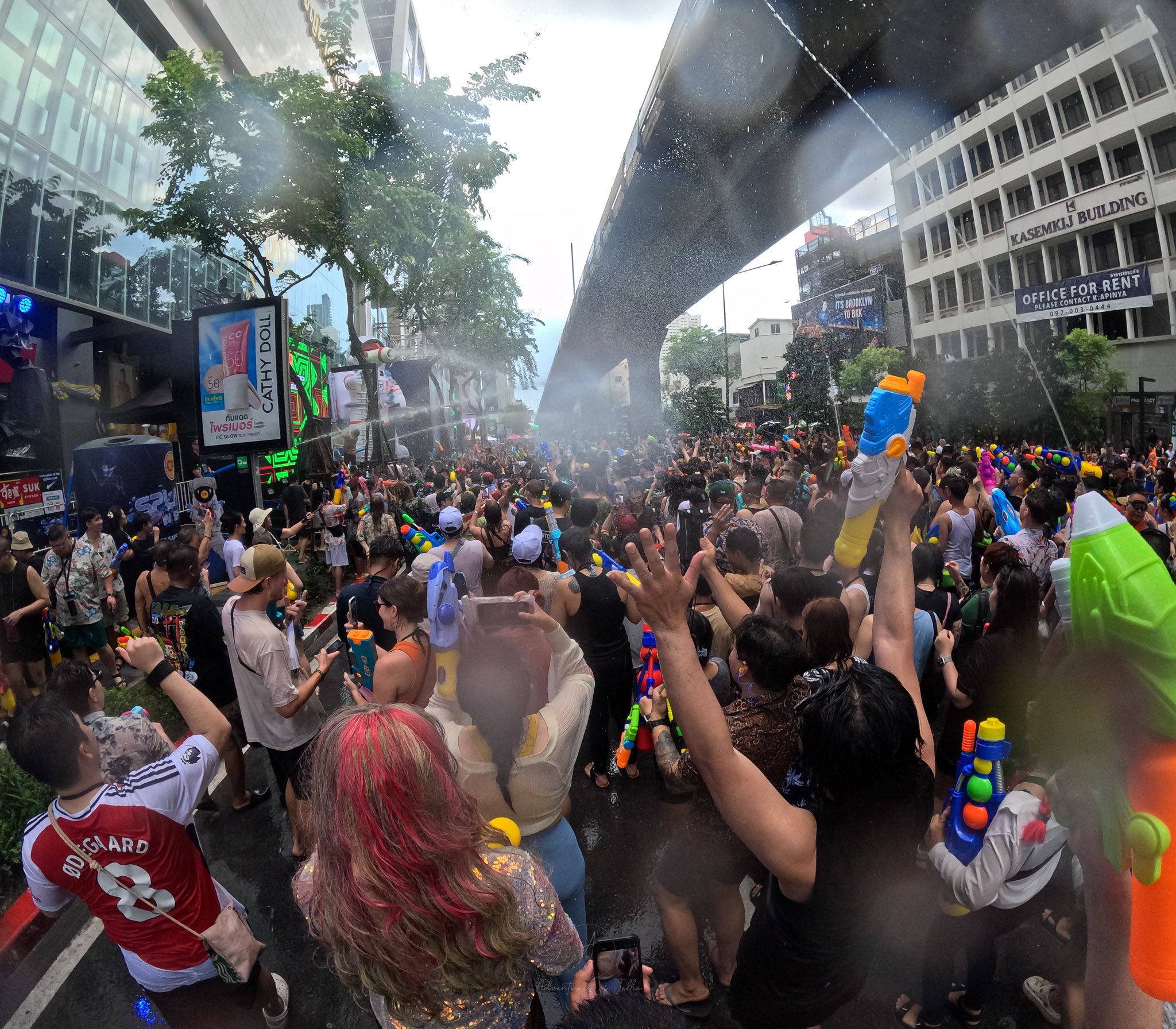 A large crowd full of revelers dance and shoot colorful water guns in Silom Road Bangkok.