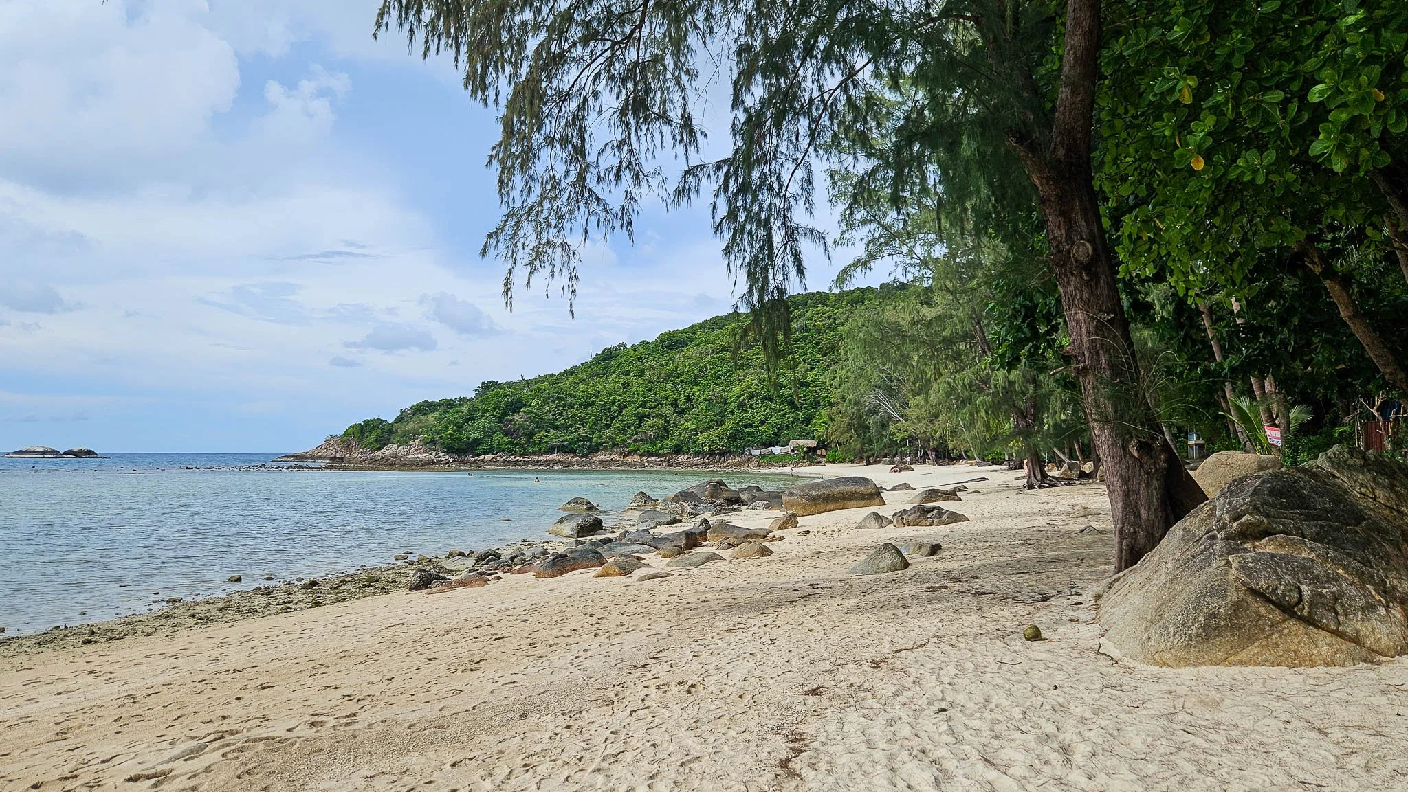 Golden sand and small boulders line the shoreline on Haad Khom Beach on Koh Phangan.