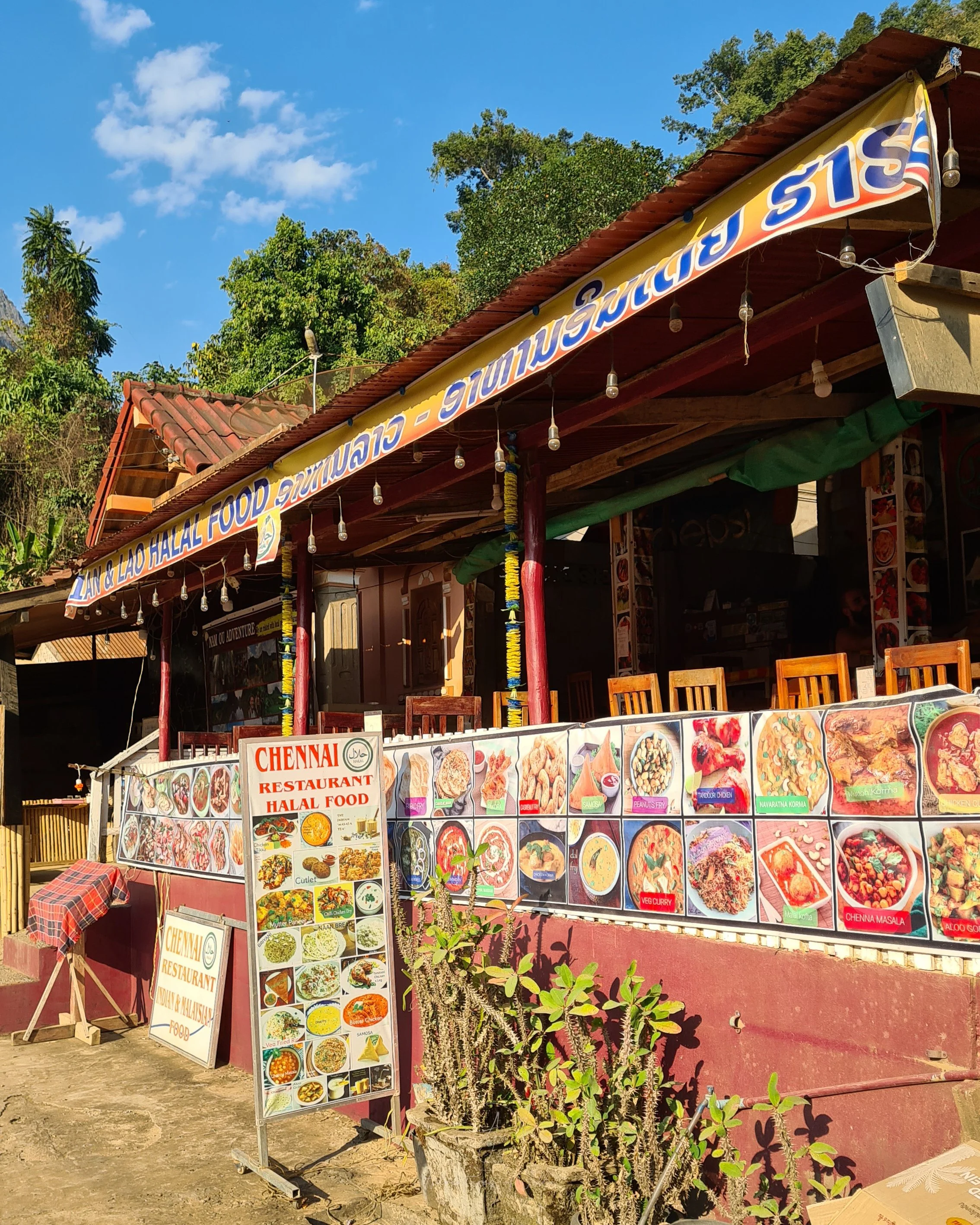 The colourful open front exterior of Nong Khiaw's Chennai Indian Restaurant is covered in posters advertising the different curry dishes available to order.