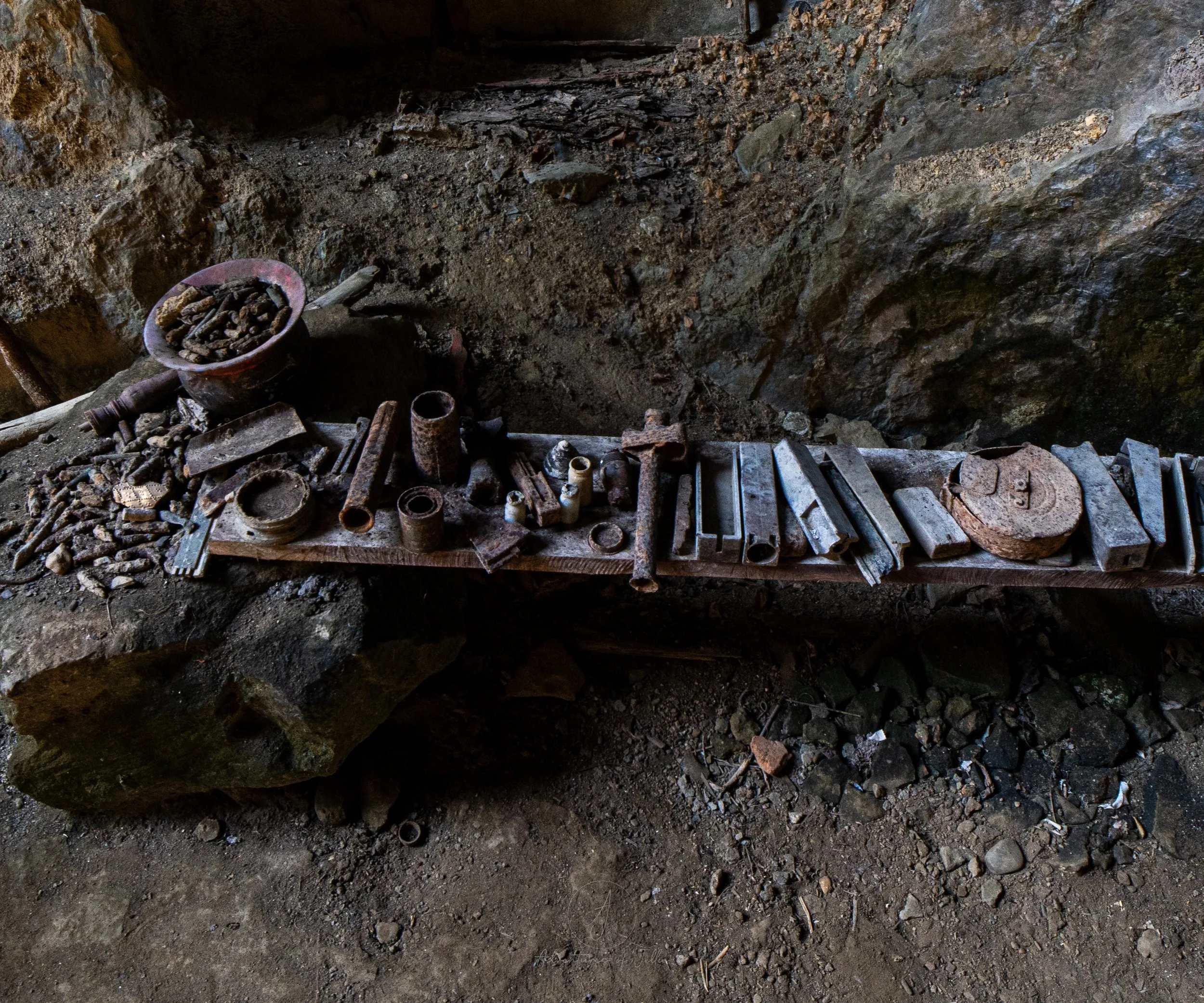 Rusty relics including old food cans, weapons and tools leftover from the Secret War lie arranged in a line on a wooden bench inside the Pha Kuang Cave in Nong Khiaw, Laos.