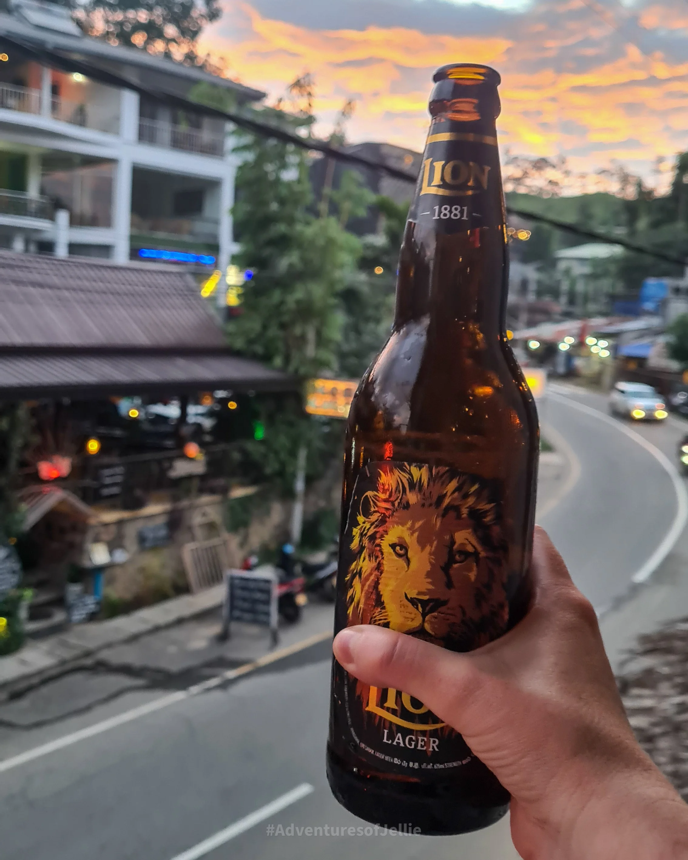 A bottle of Lion larger is raised in salute in front of the setting sun in Ella, Sri Lanka.