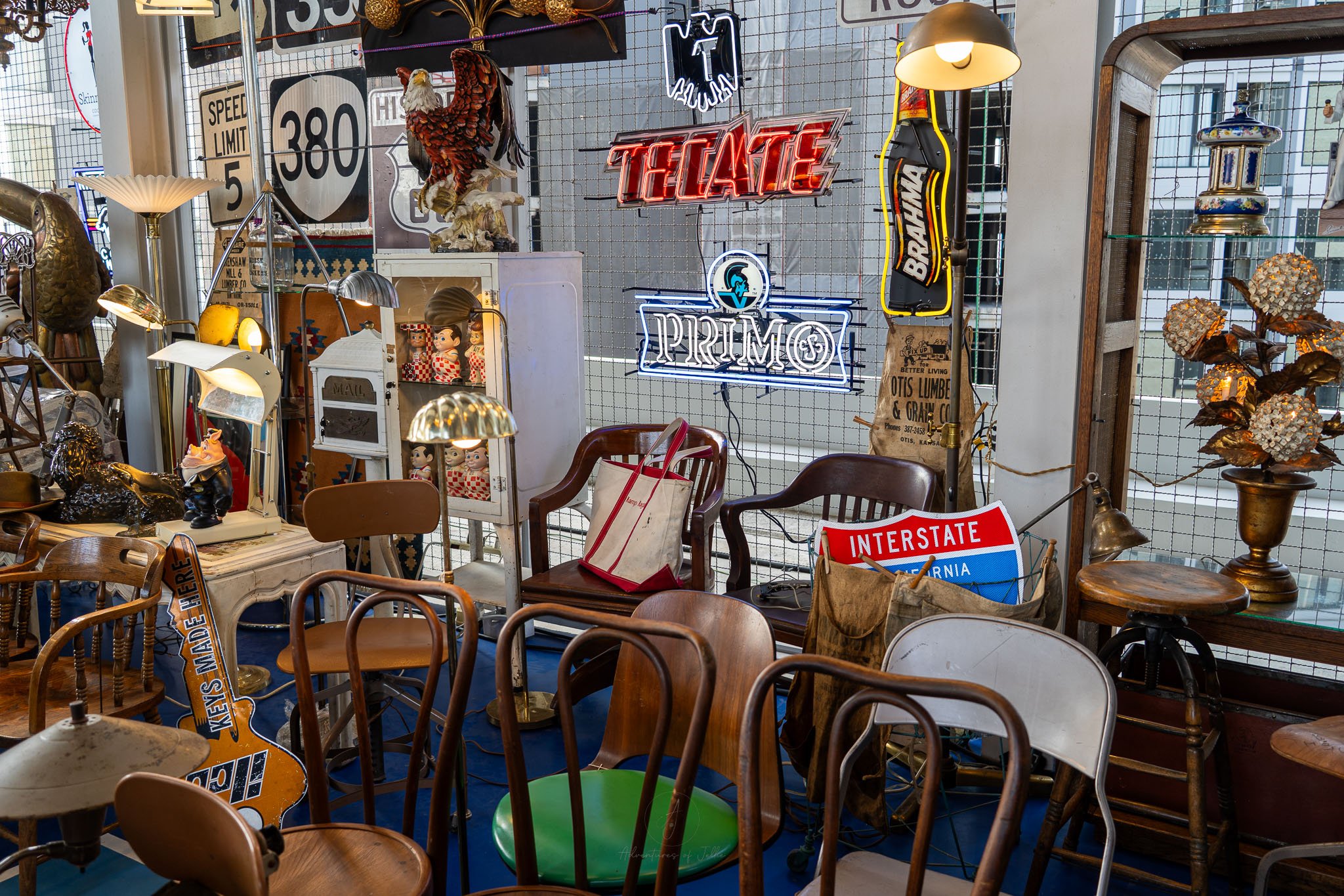 A flea market stall is stuffed full of old wooden chairs, neon lights and old USA style road signs.