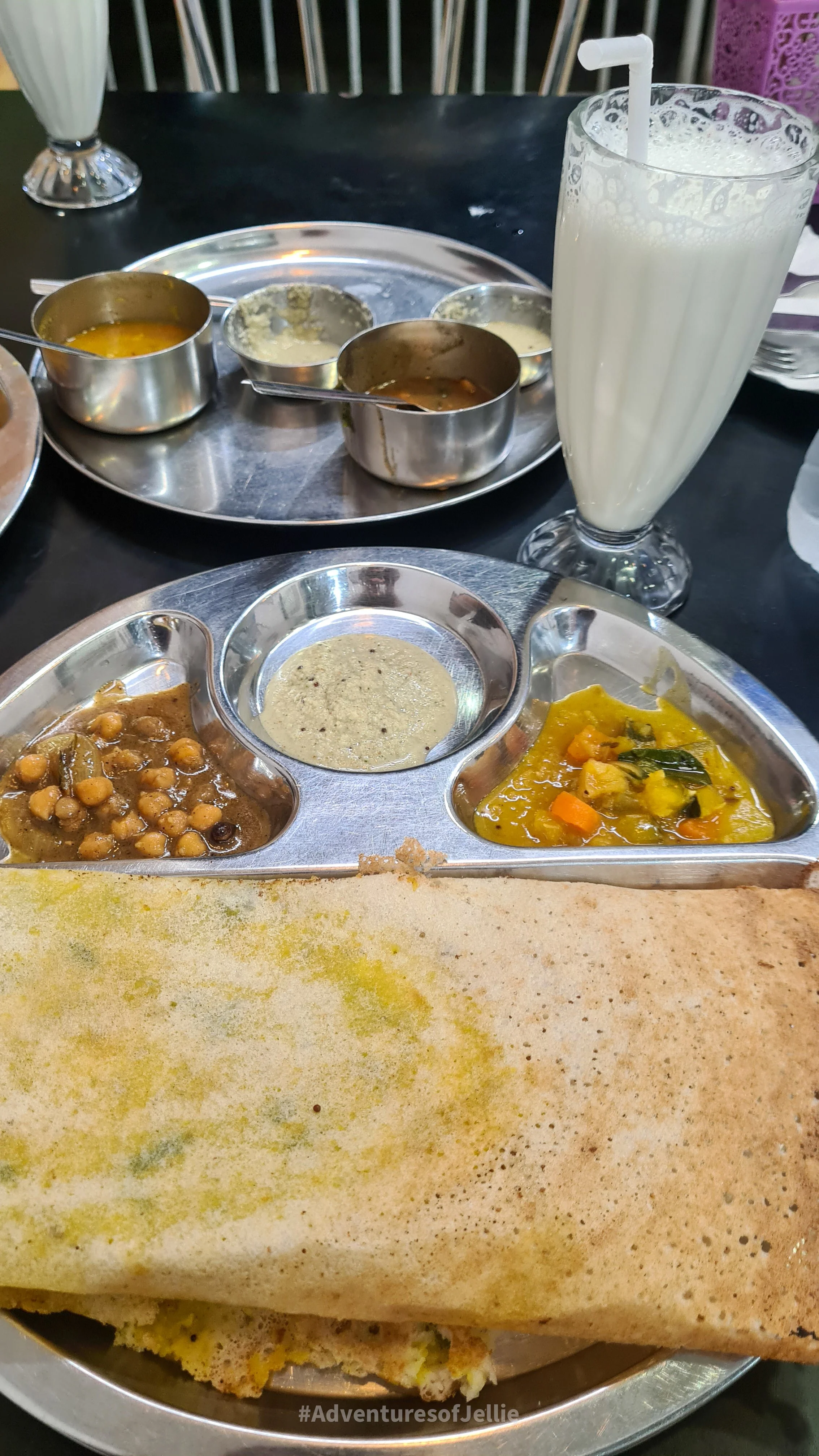 A plate of masala dosa accompanied by chick pea and vegetable curries and coconut chutney. A glass of lassi sits along side. Photo taken in the Sri Krishna Dosai restaurant in Kandy, Sri Lanka.