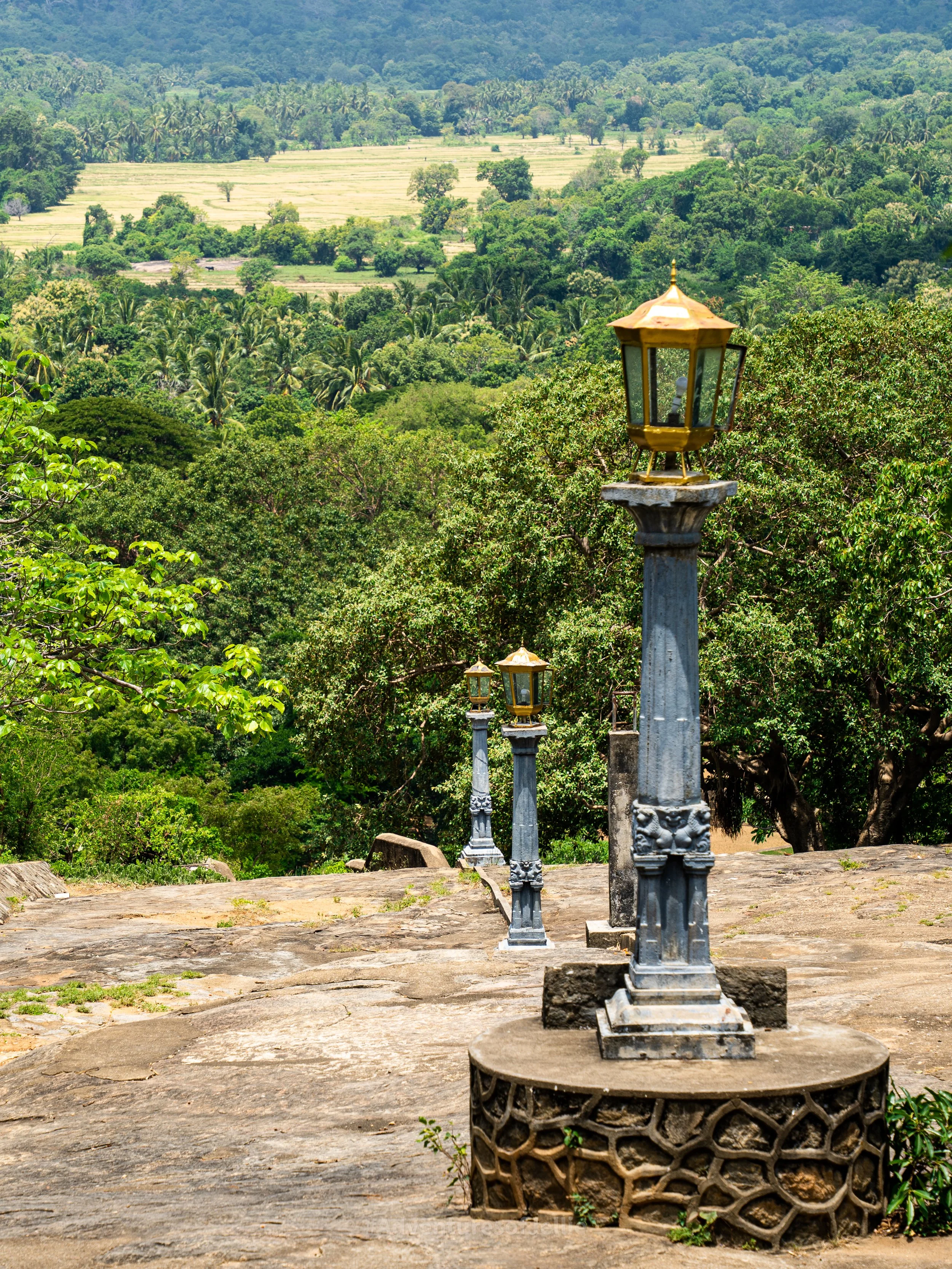 A steep path marked with lamposts leads down to the Giant Golden Buddha at the Dambulla Royal Cave Temple.
