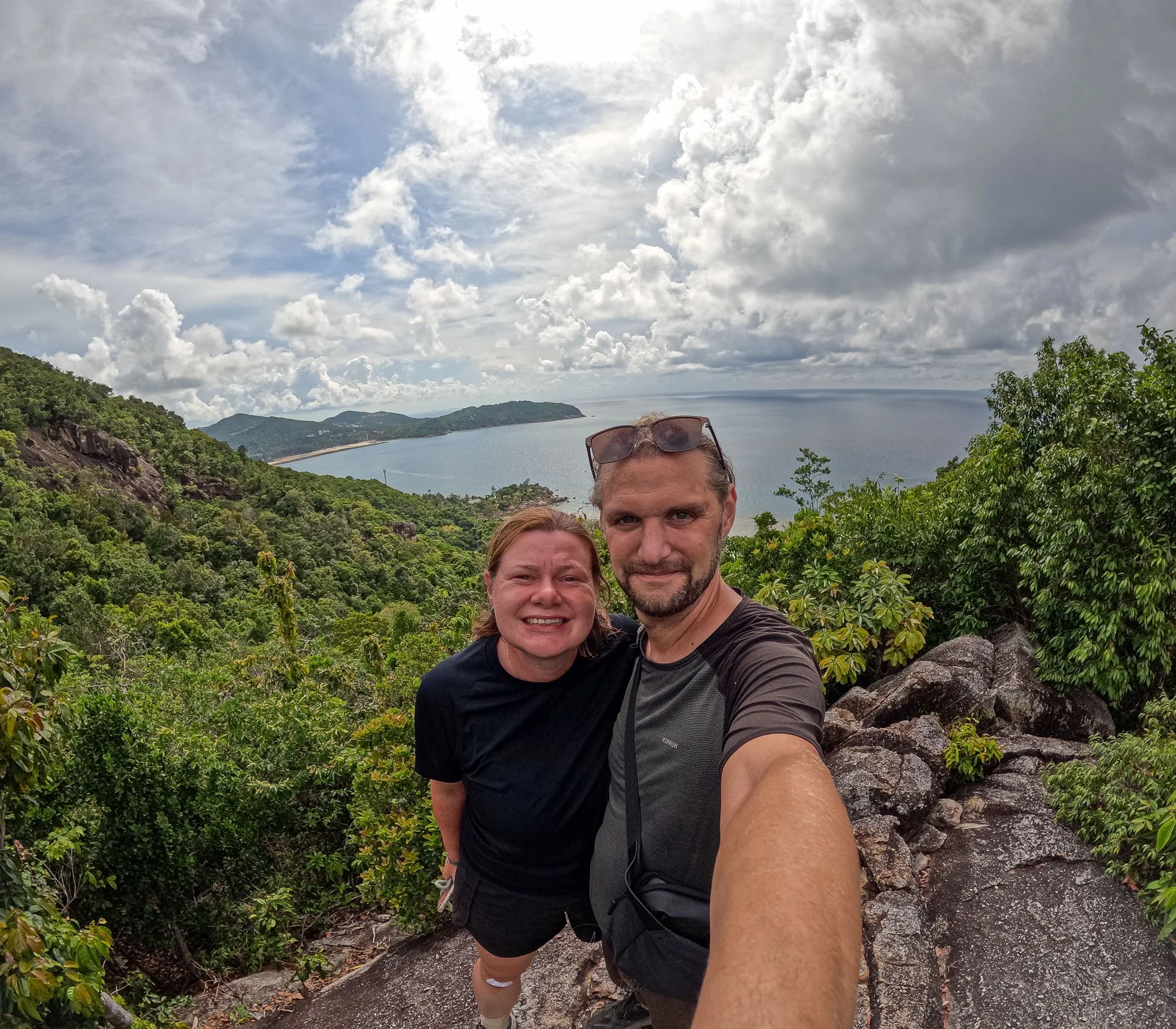 Adventures of Jellie pose for a GoPro selfie on top of the Haad Khom Viewpoint on Koh Phangan. Behind them the coastline and shore of Chaloklum Beach is visible.