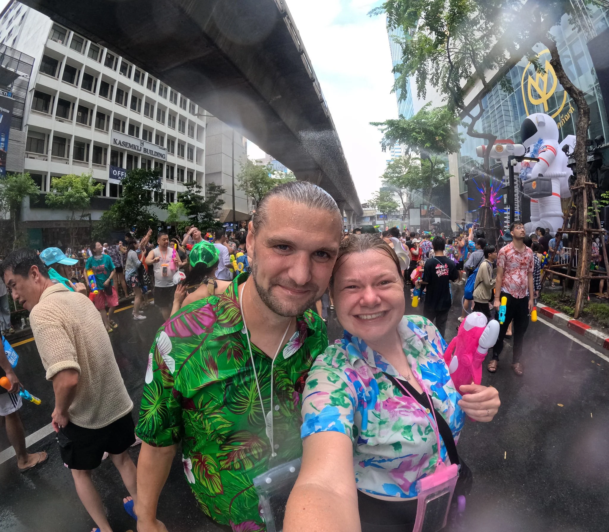 John and Ellie, dripping wet smile for the camera. Around their necks are plastic waterproof pouches for their phones.